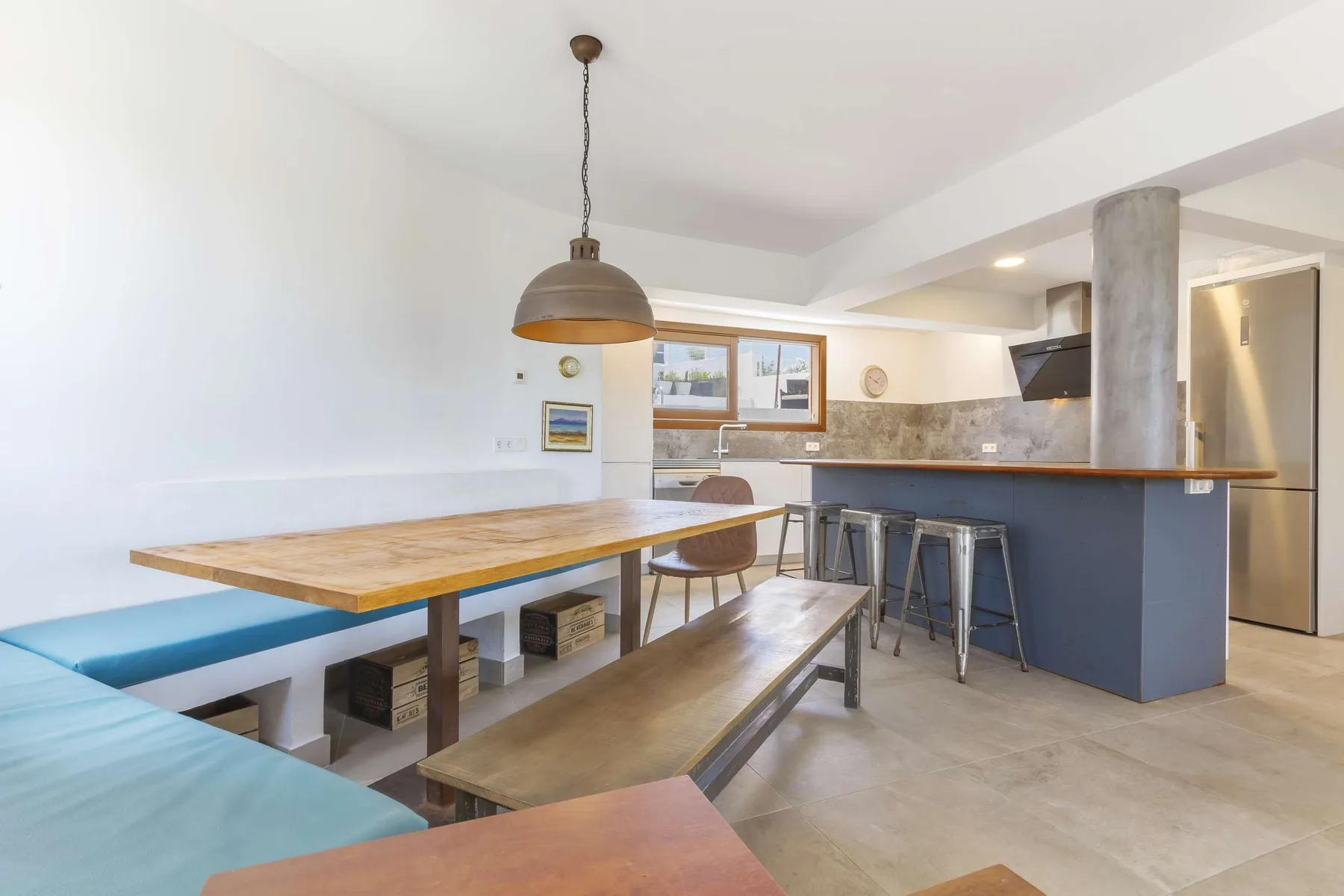 A dining and kitchen area with a long wooden table and counter seating.
