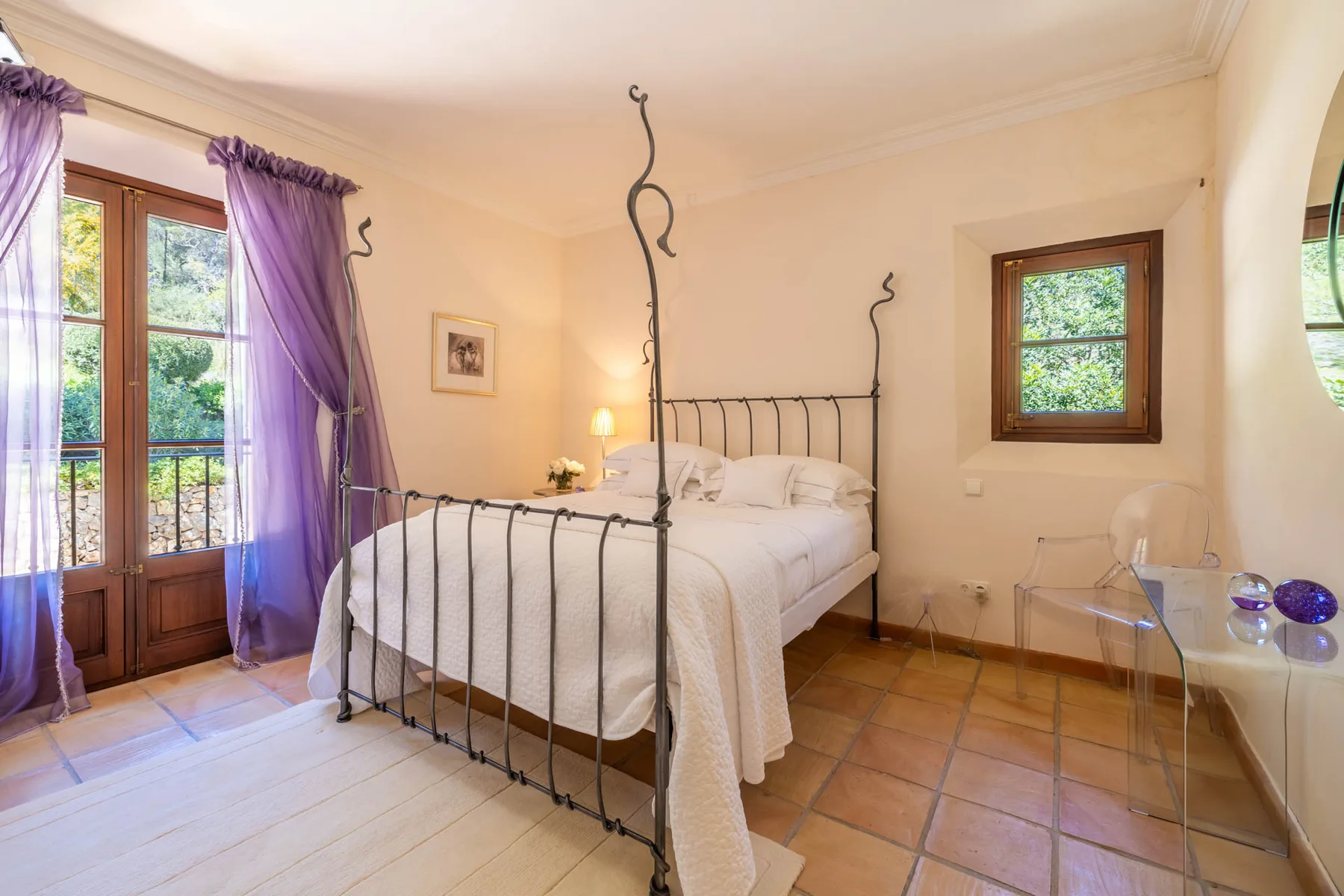 A bedroom with a white bed, dark metal frame, and purple curtains.