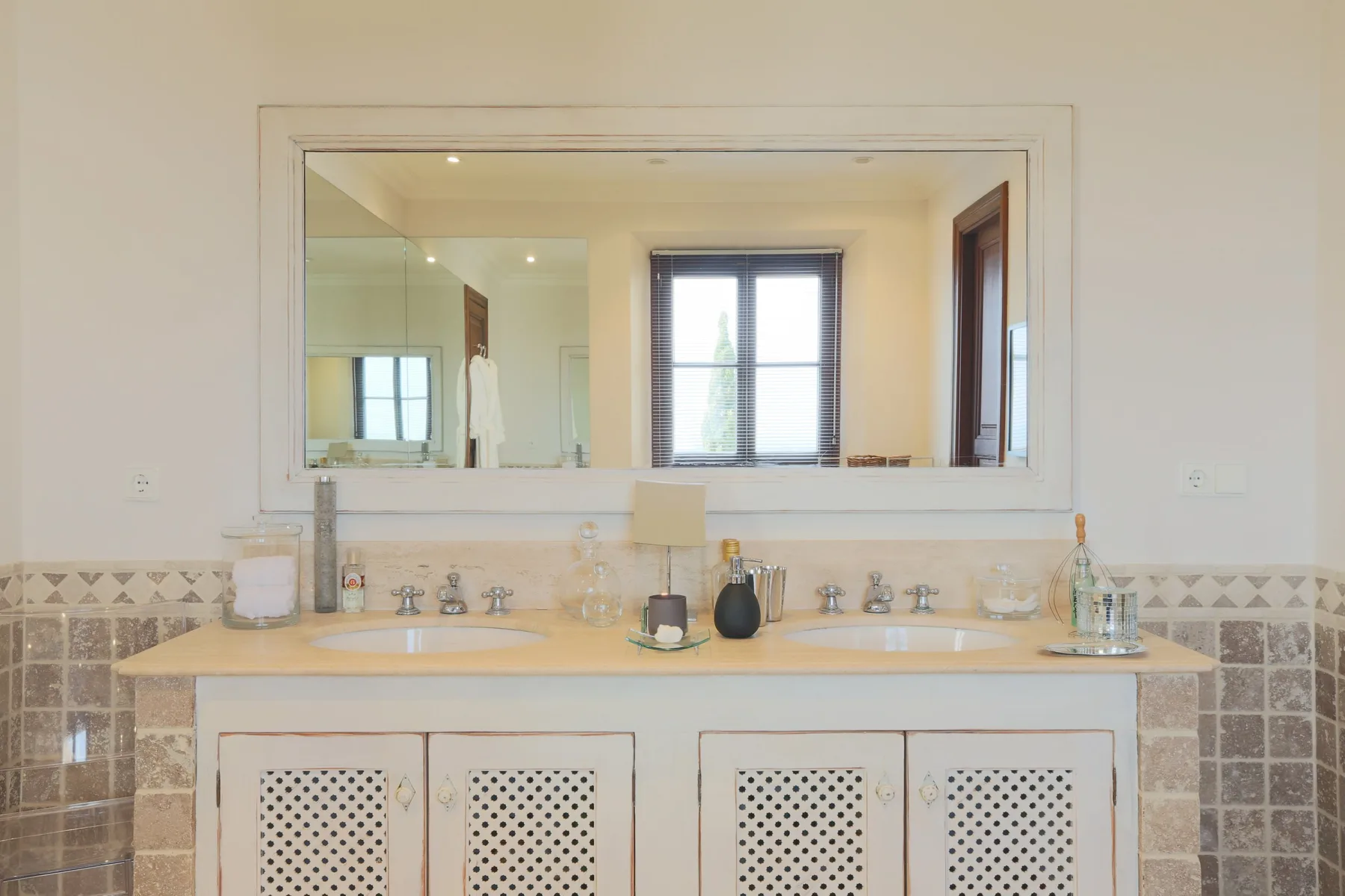 A bathroom vanity with a wide mirror and tiled walls.
