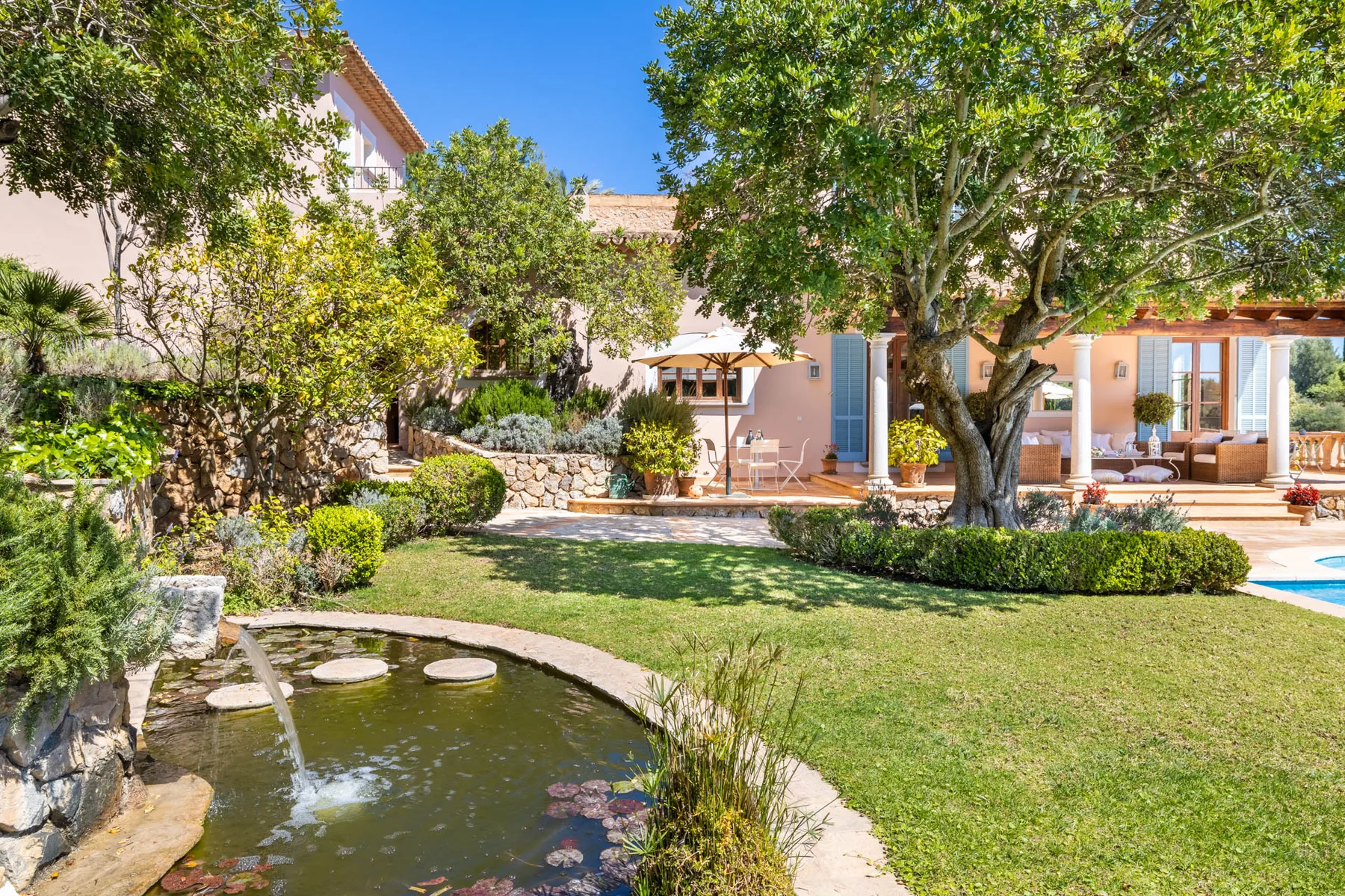 A landscaped garden with a small pond and a patio beside the house.