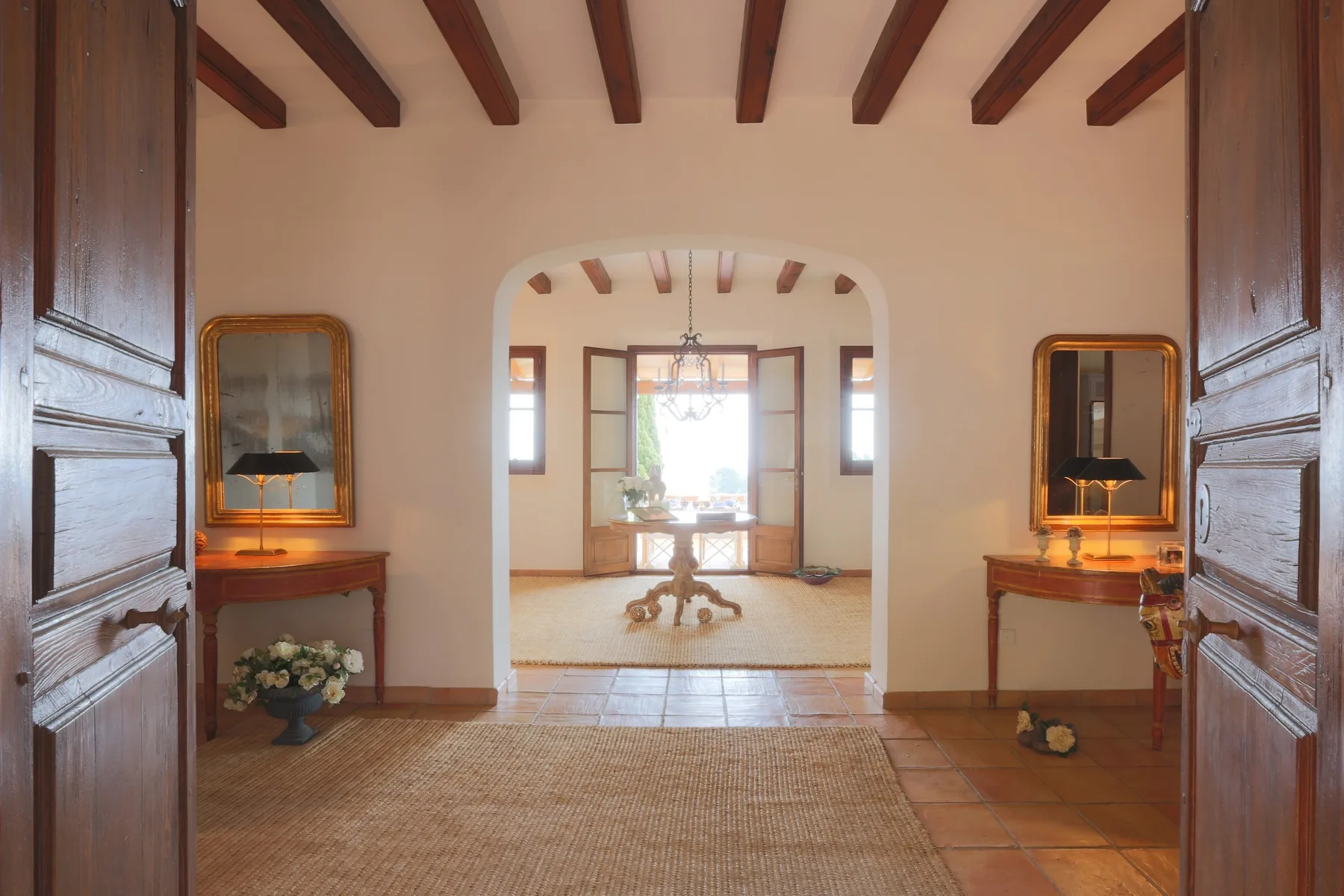 A bright interior hallway opens into a room with a table and large windows.