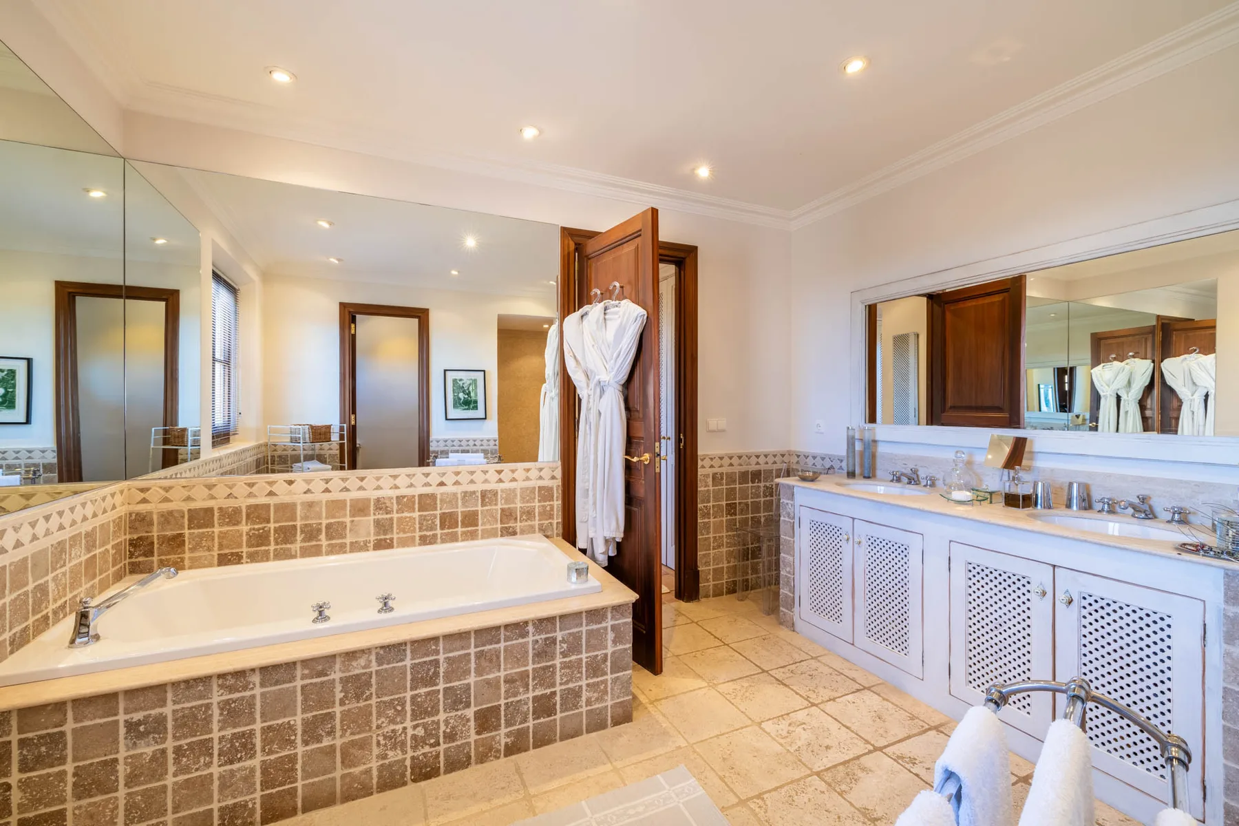 A bright bathroom with a tiled bathtub and a wide vanity.
