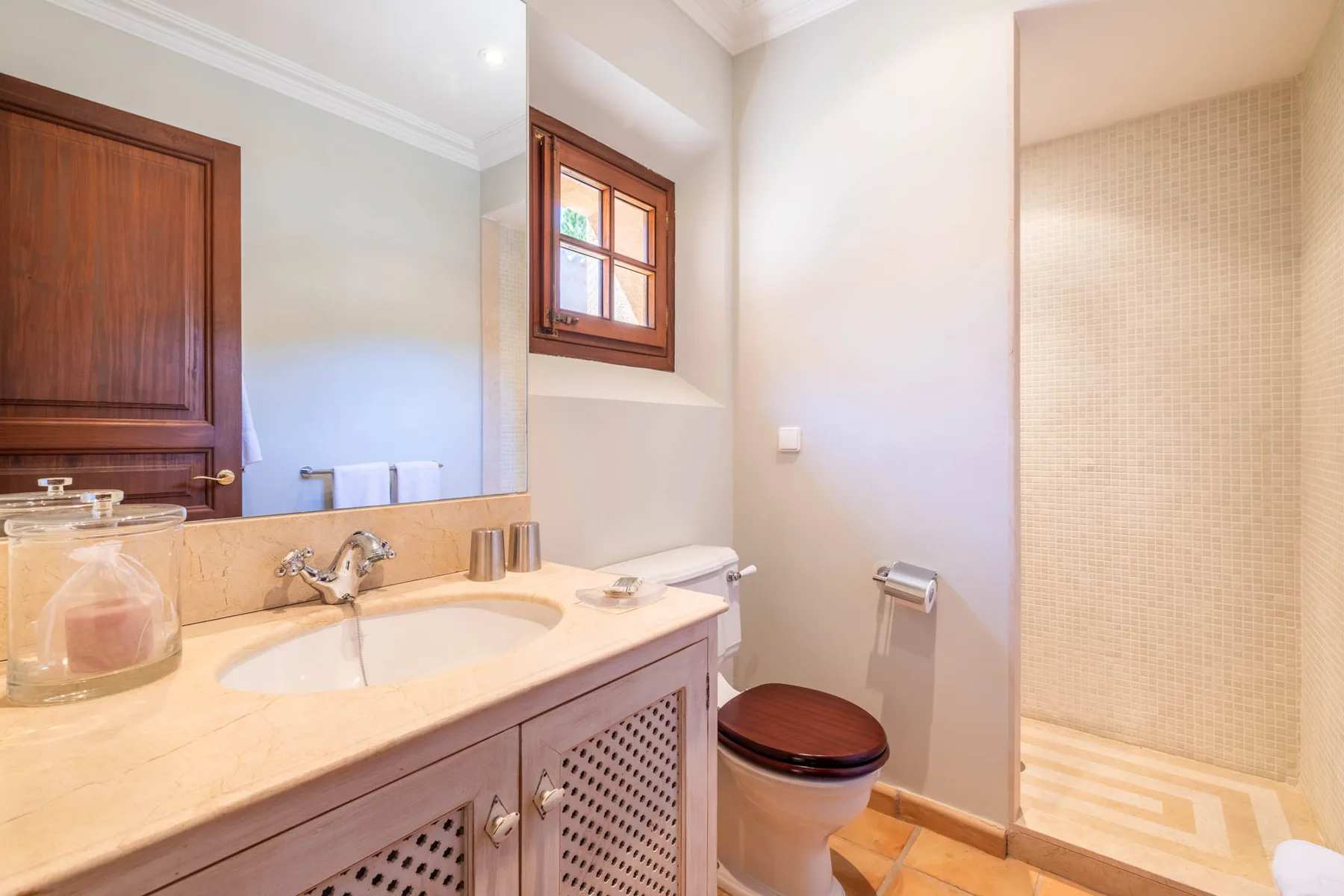 A bathroom with a sink vanity, toilet, and tiled shower area.