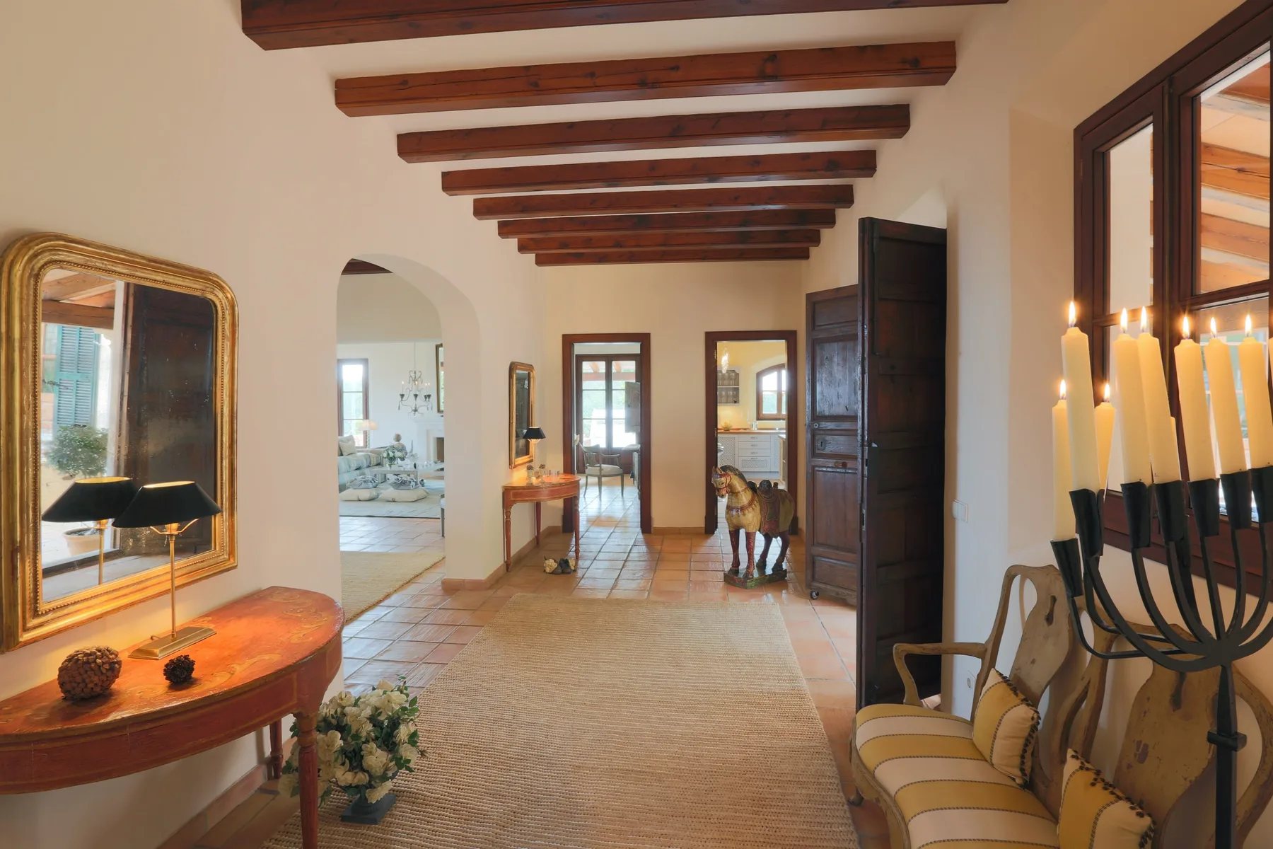 A tiled entry hall with exposed ceiling beams and seating along the walls.