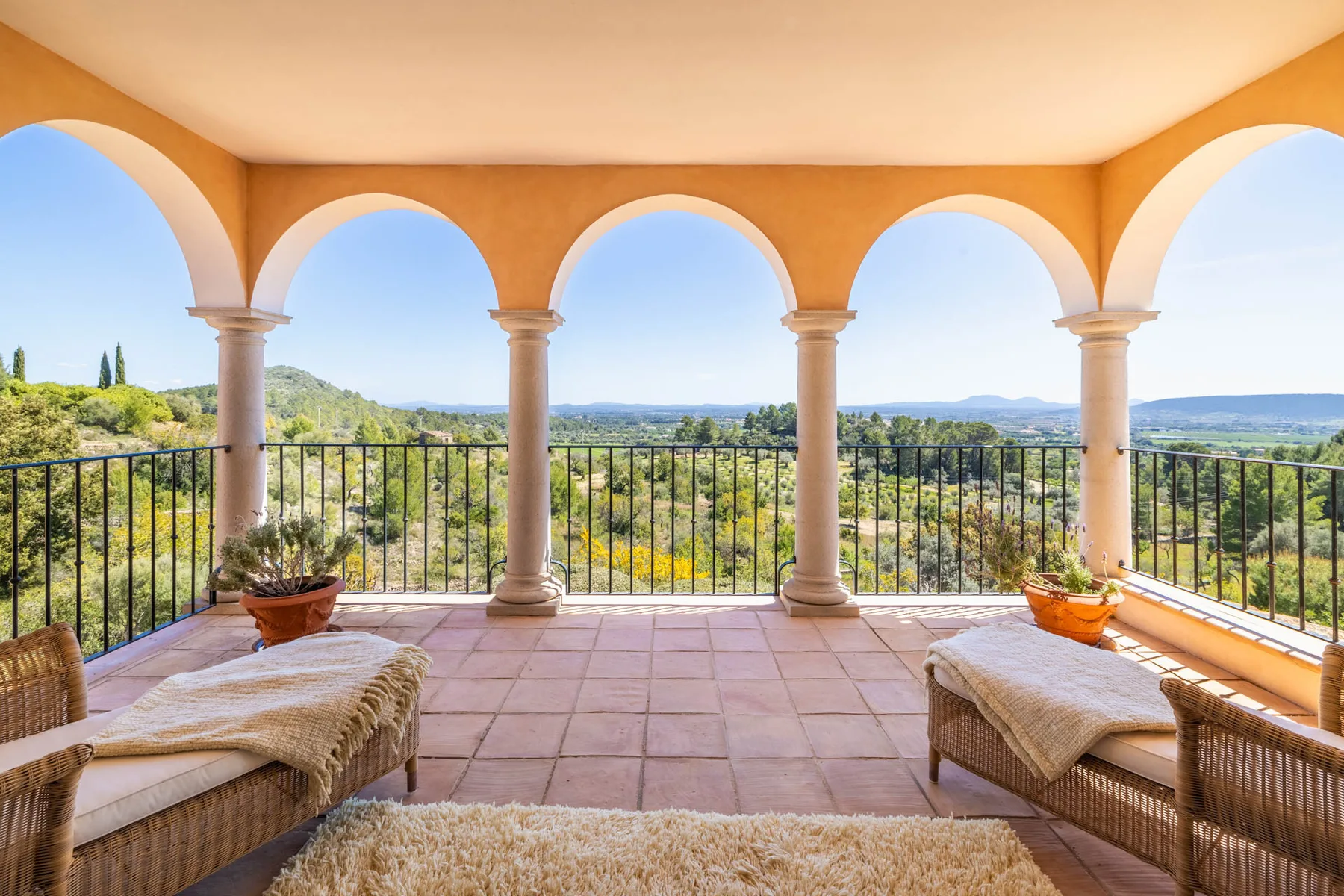 A tiled terrace with arched openings overlooks a green landscape.