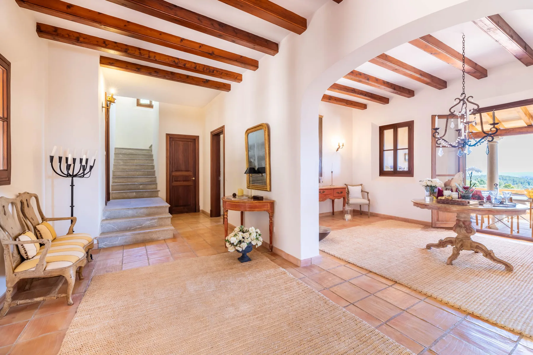 A bright interior entry hall opens into a sitting area with exposed wooden ceiling beams.