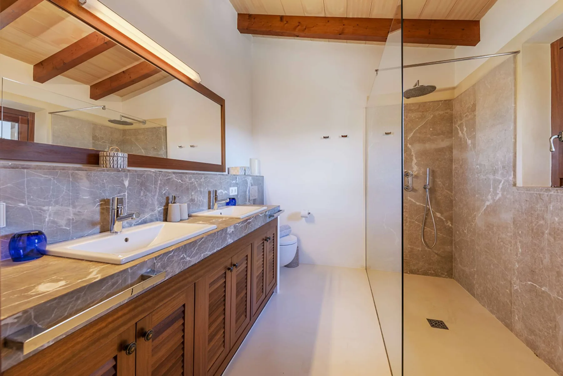 A bathroom with a long vanity, sink, and glass-enclosed shower.