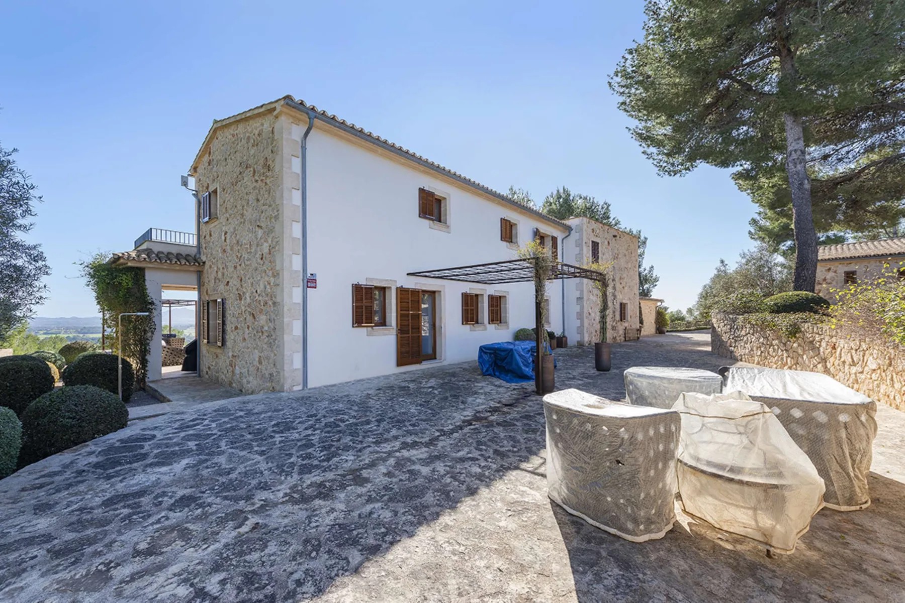 A white house with stone accents opens onto a paved outdoor patio.