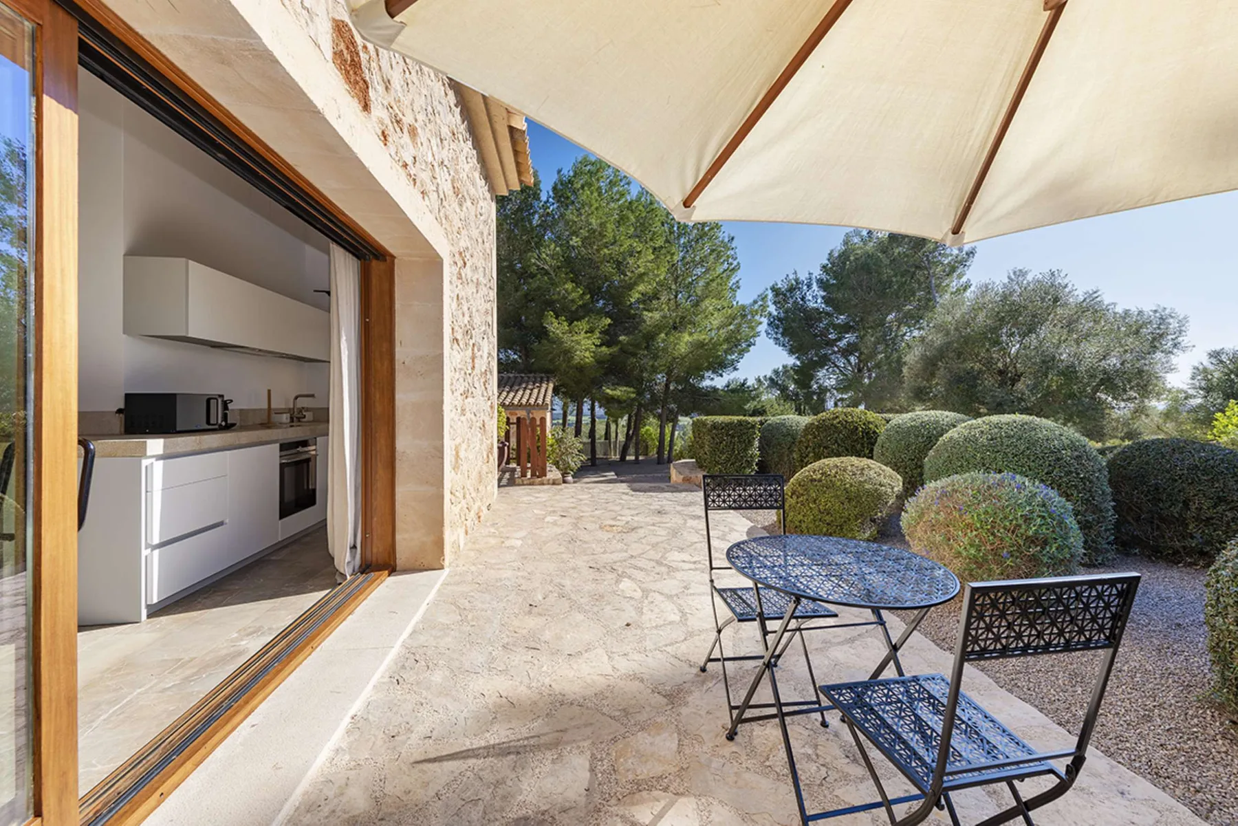 An outdoor patio with a small table and seating beside an open kitchen.