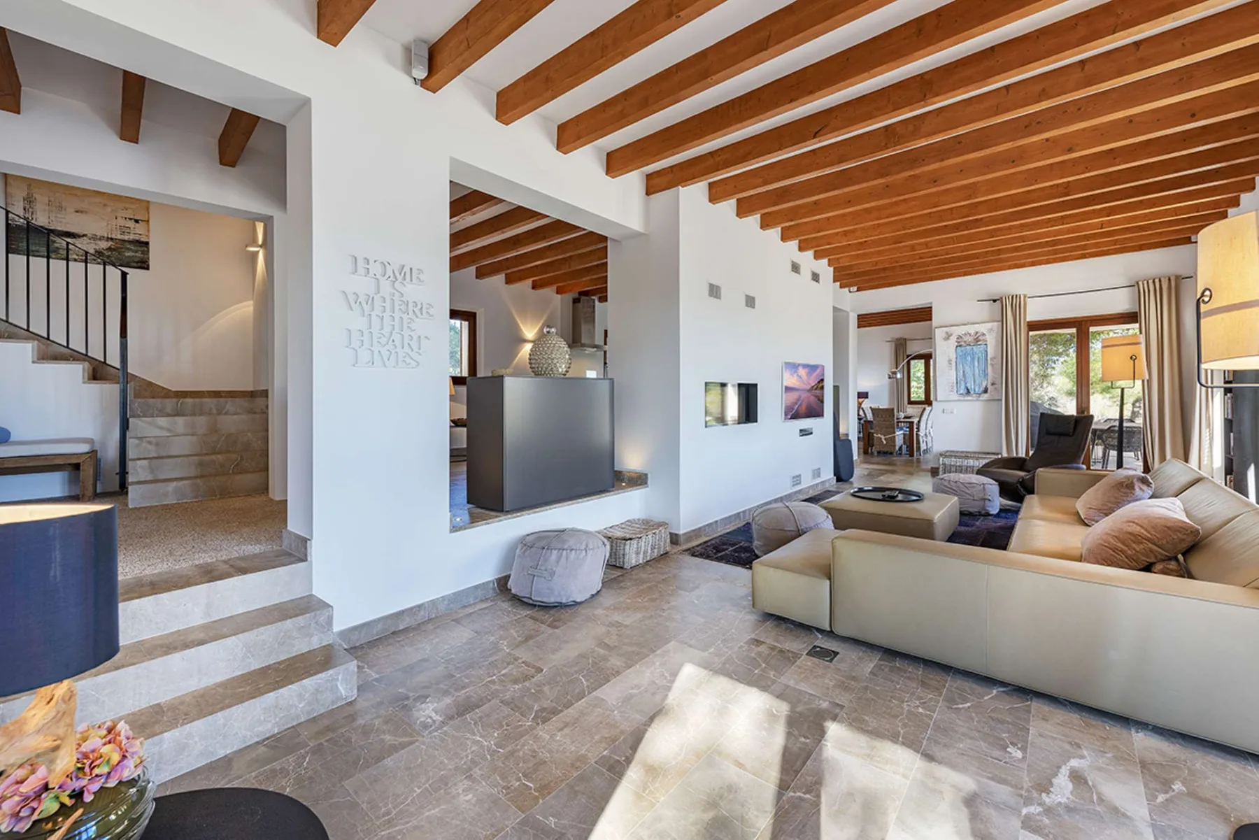 A spacious living room with exposed wooden ceiling beams and a seating area.