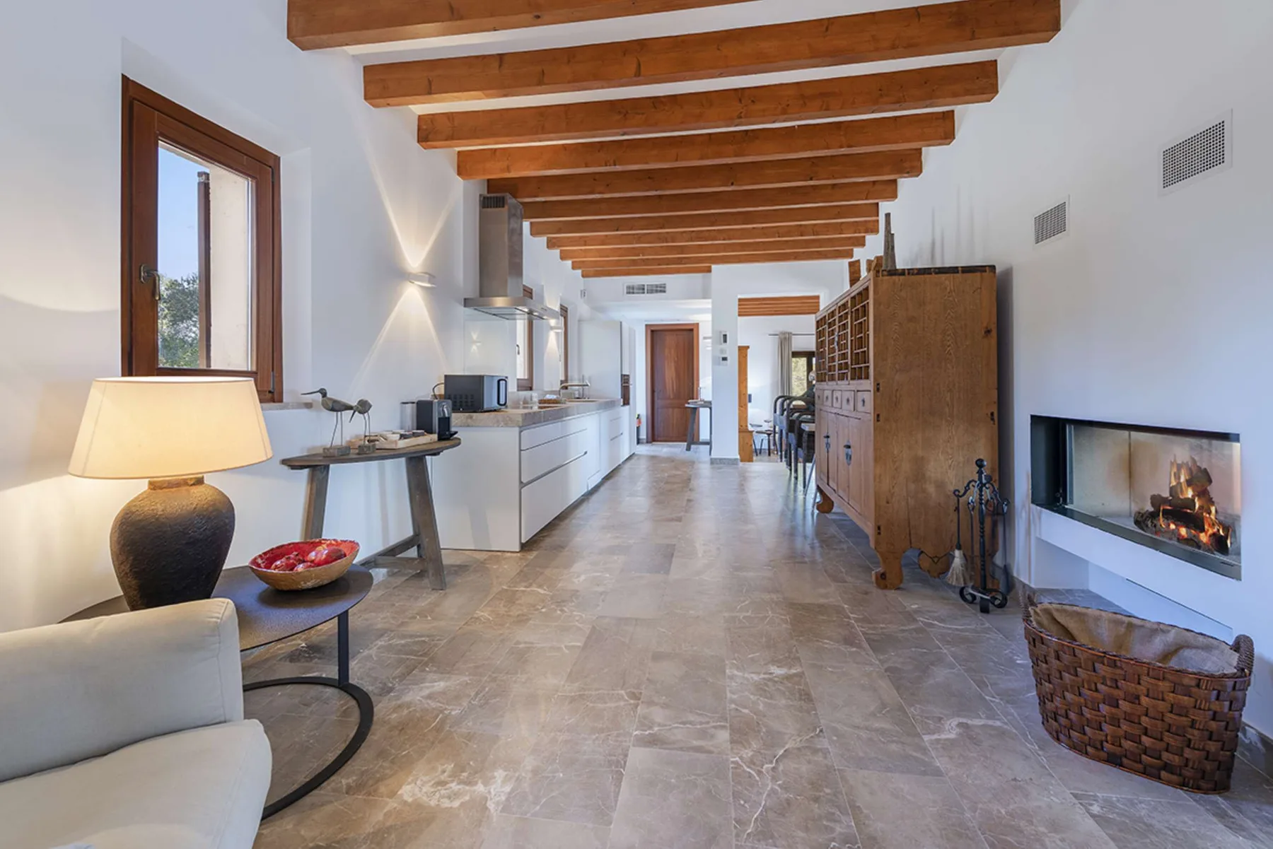 A bright open-plan living and kitchen area with exposed wooden ceiling beams.