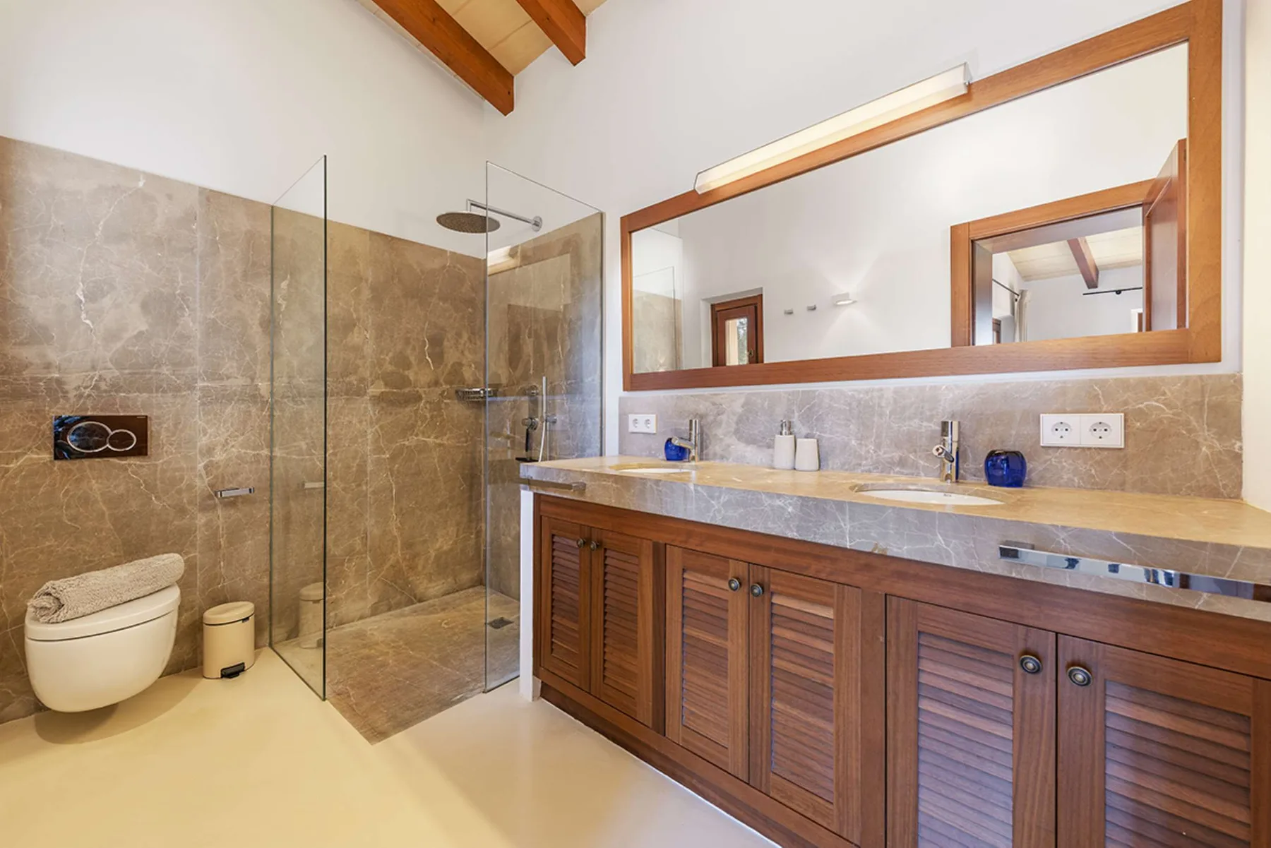 A bathroom with a long vanity, wide mirror, and glass shower.