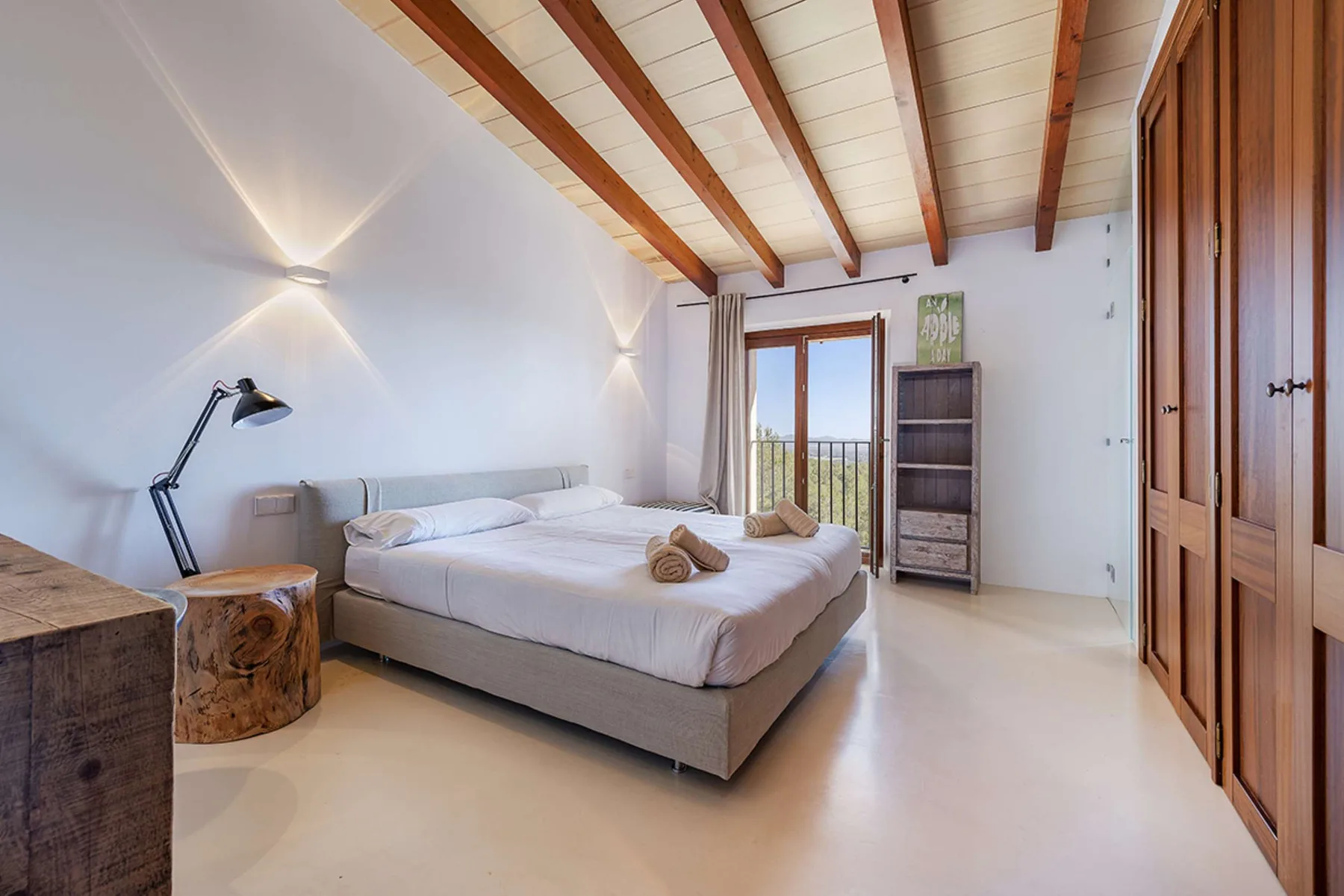 A bedroom with a bed, bedside lamp, and wooden wardrobes.