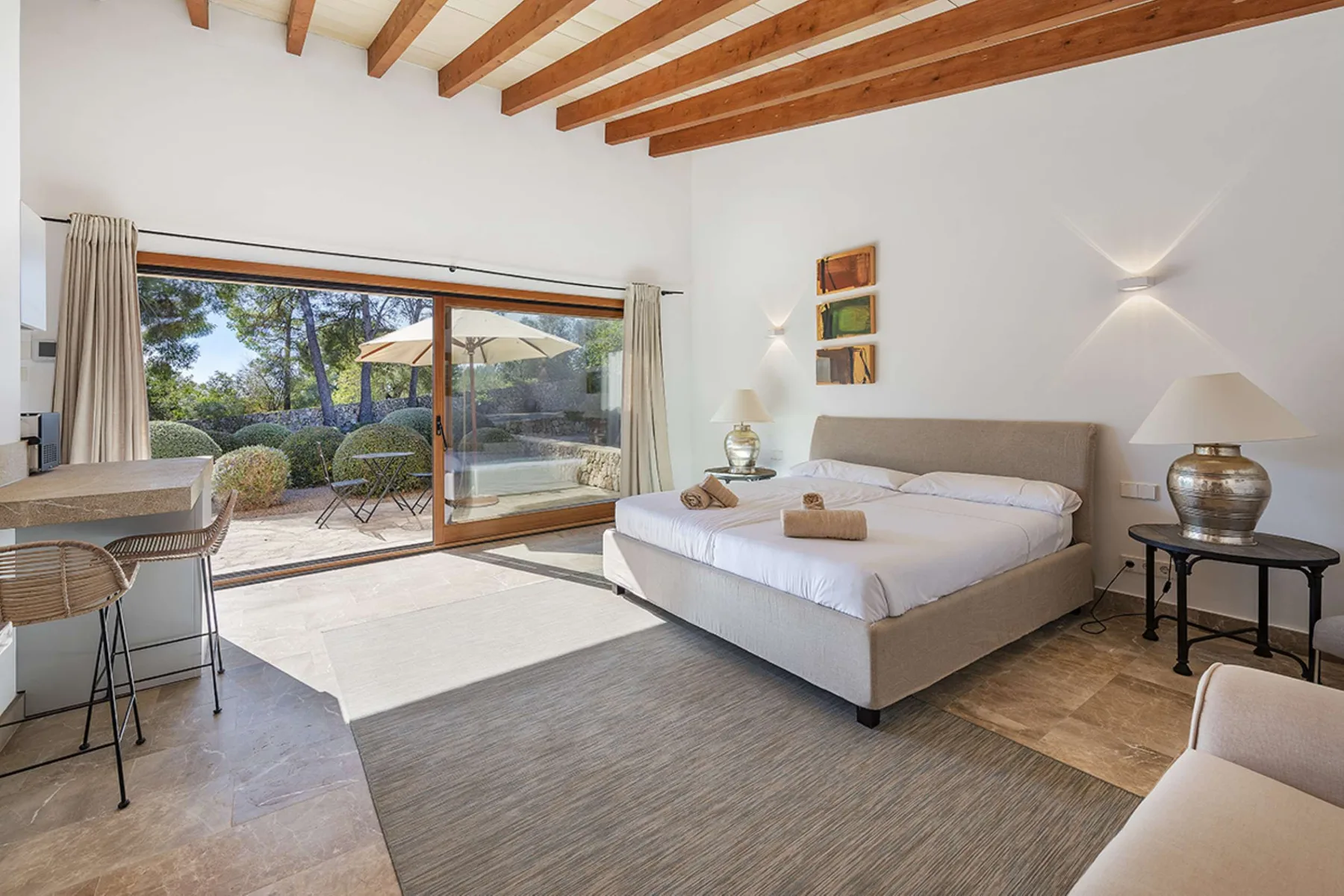 A bright bedroom with a large bed and sliding glass doors opening onto a patio.