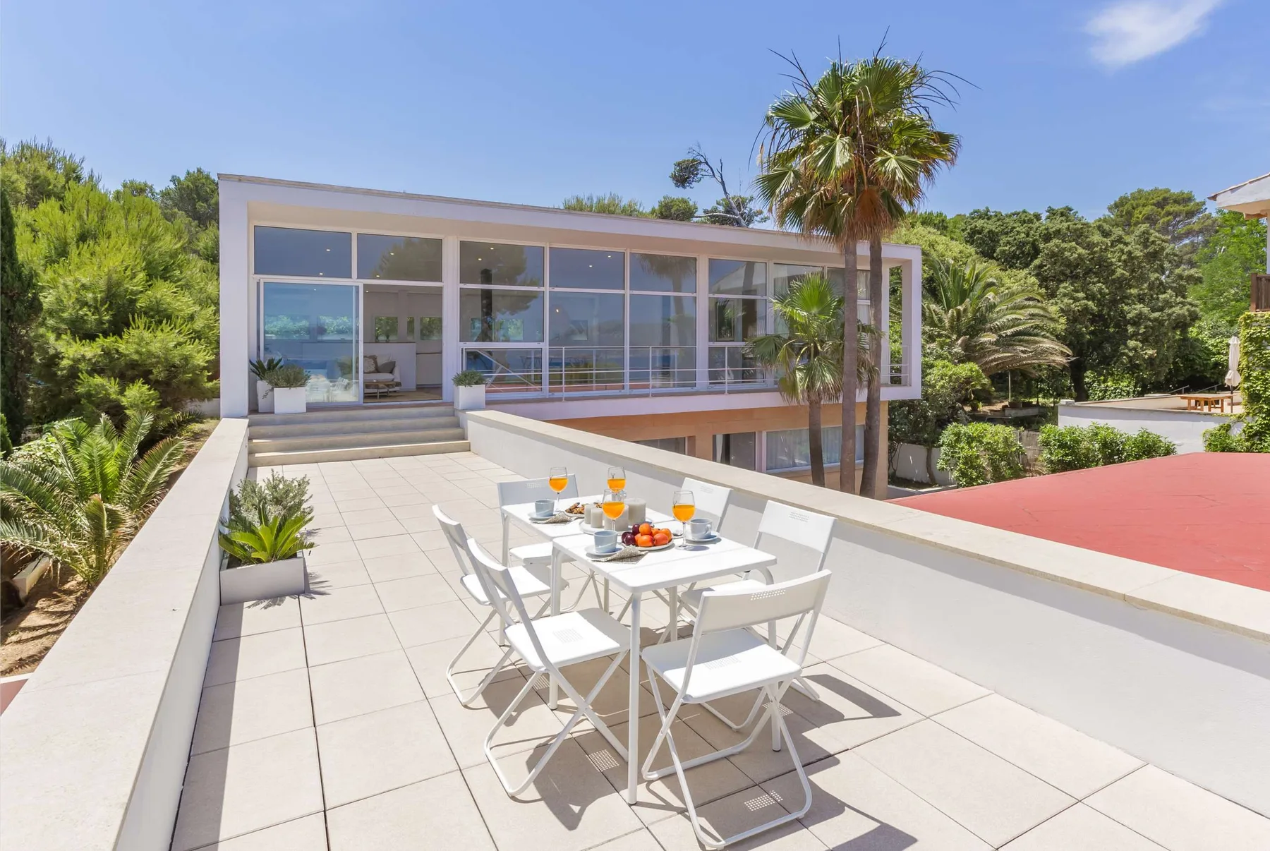 A rooftop terrace with outdoor dining furniture beside a glass-fronted building.