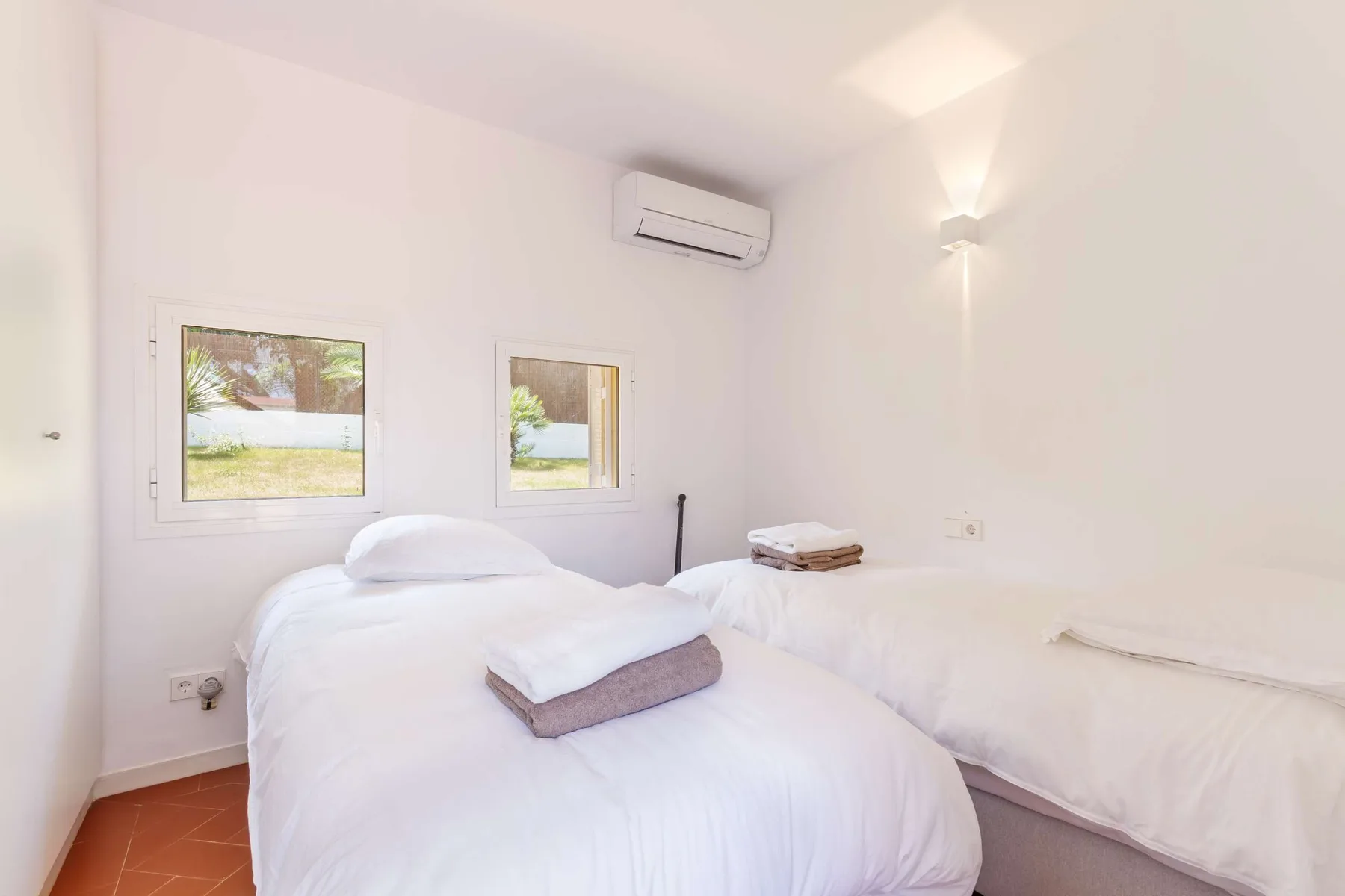 A bright bedroom with a white bed and two windows.