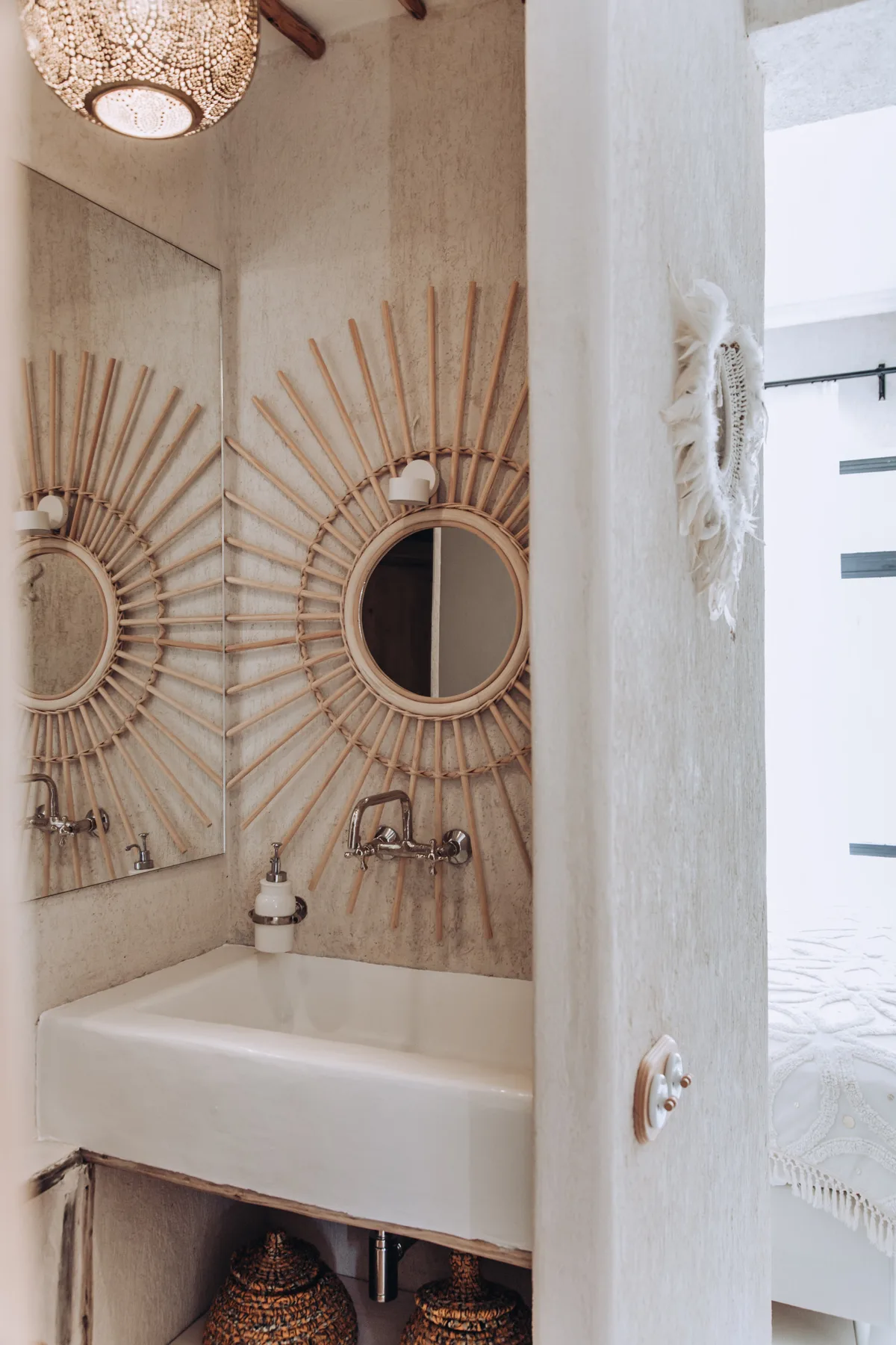 A bathroom vanity with a wide basin, wall mirrors, and woven decorative accents.