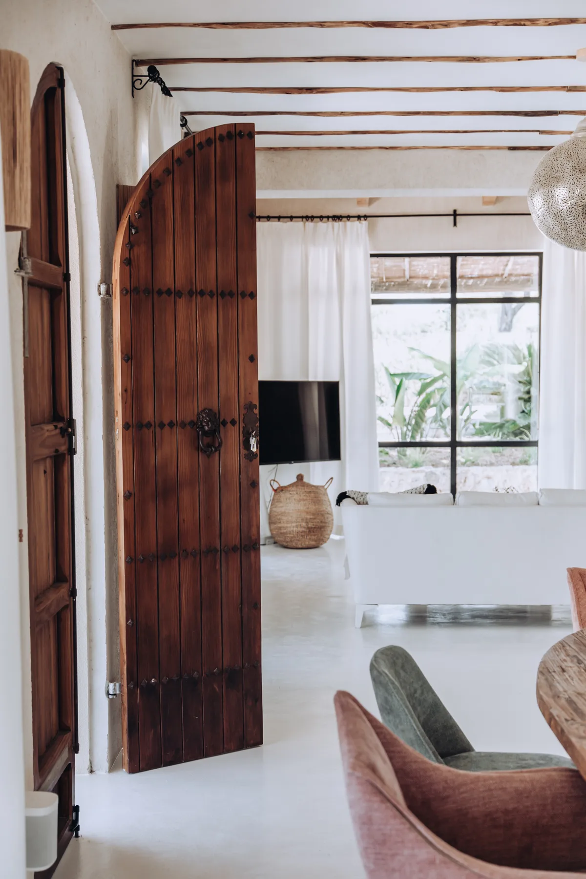 A bright living room with an open wooden door and large windows.