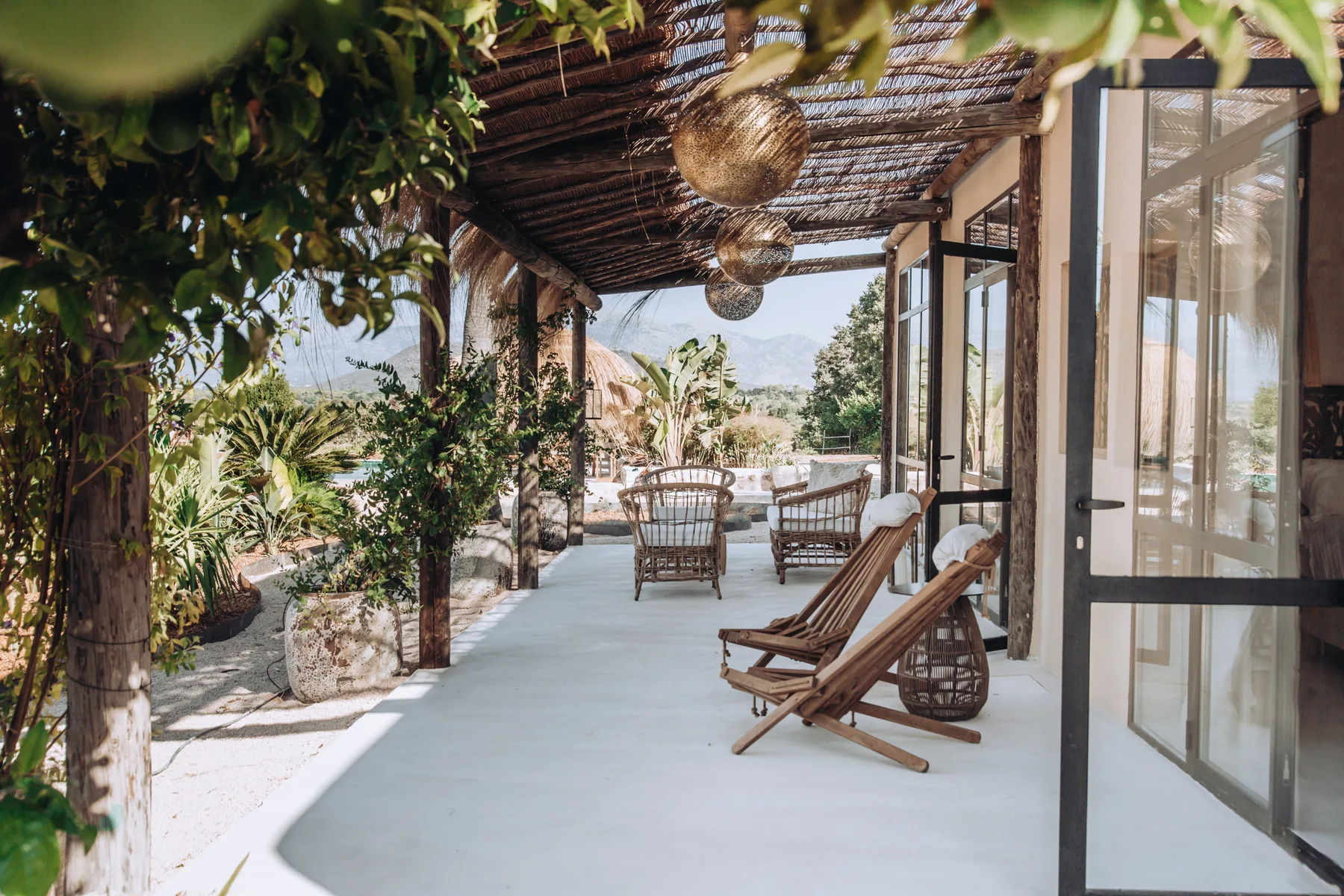 A covered outdoor patio with lounge seating and plants.
