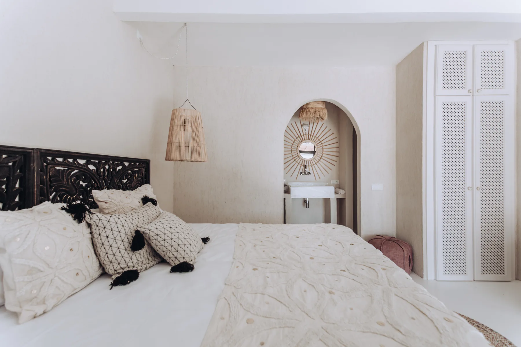 A bedroom with a bed, patterned bedding, and an arched vanity alcove.