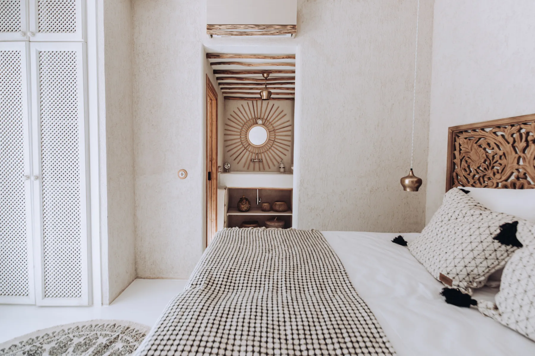 A bedroom with white bedding and an intricately carved wooden headboard.