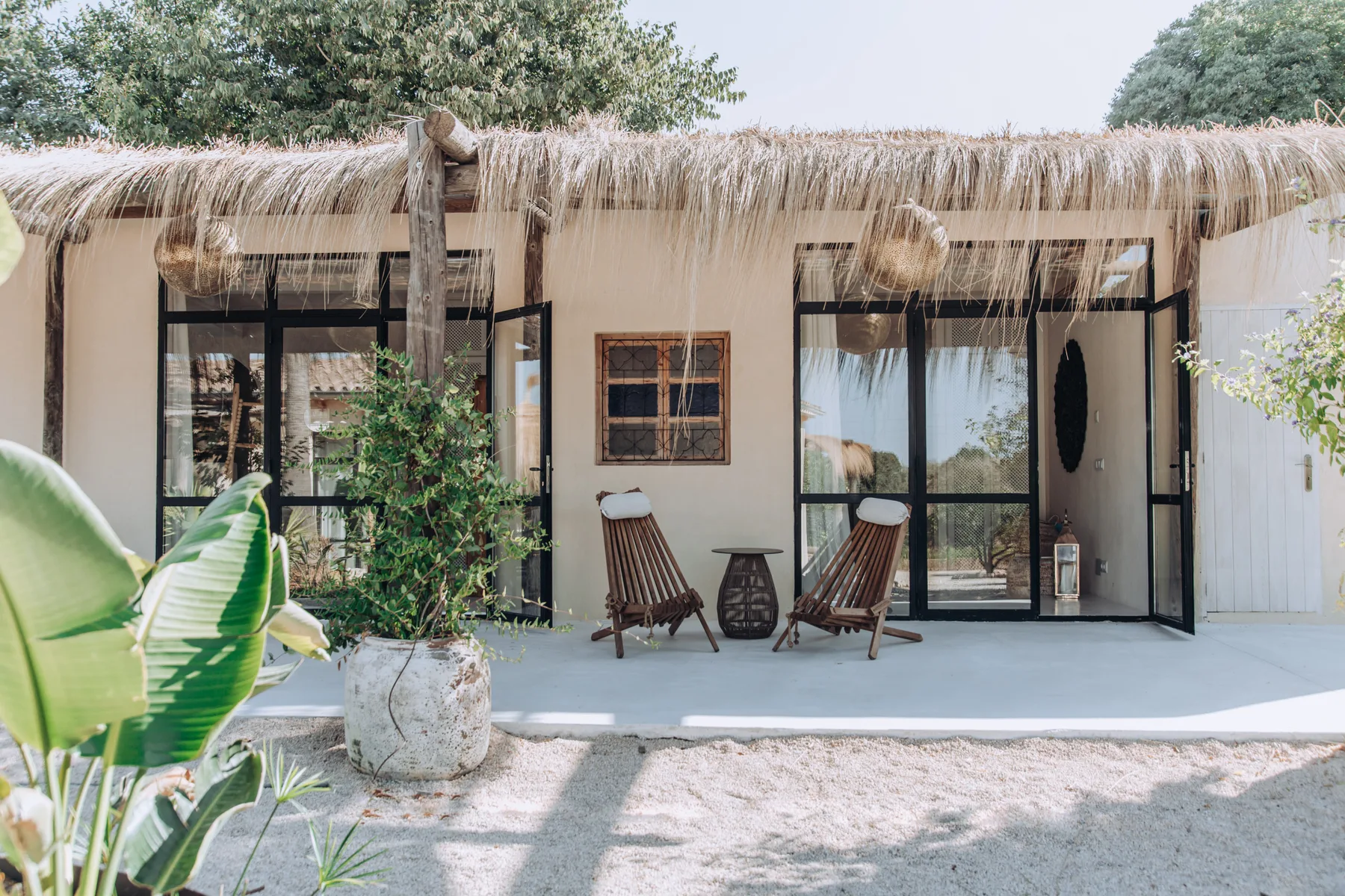 A low, thatched-roof building with glass doors and outdoor seating.