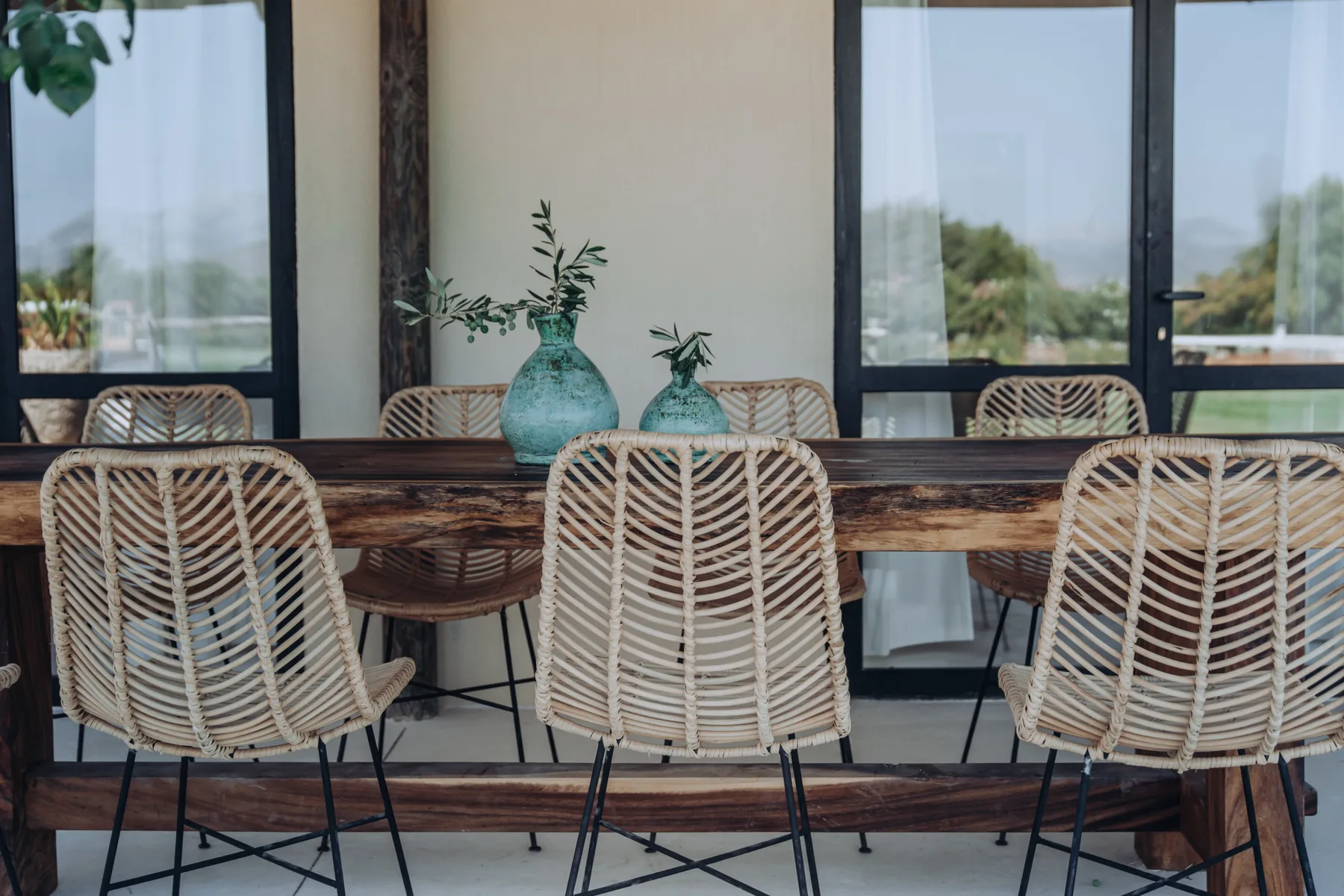 An outdoor dining area with a long wooden table and woven seating.