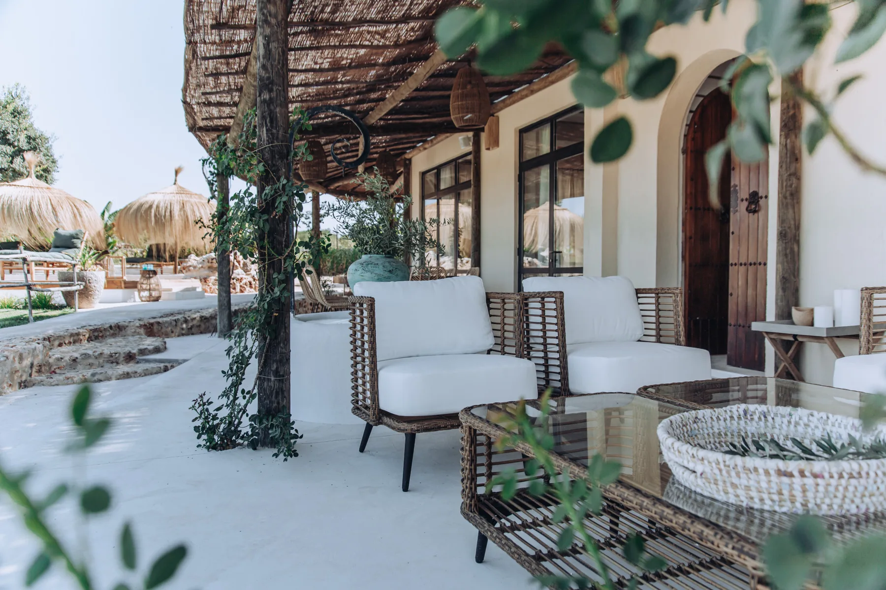 An outdoor patio with cushioned seating beneath a woven shade canopy.