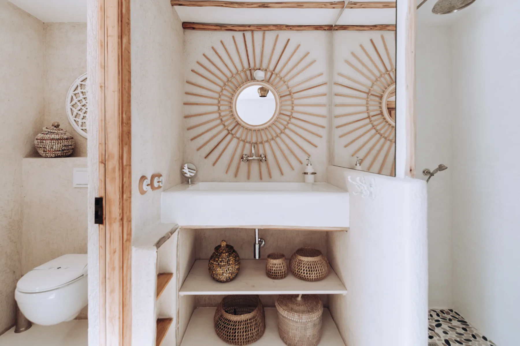 A bathroom vanity with round mirrors and woven baskets on open shelves.