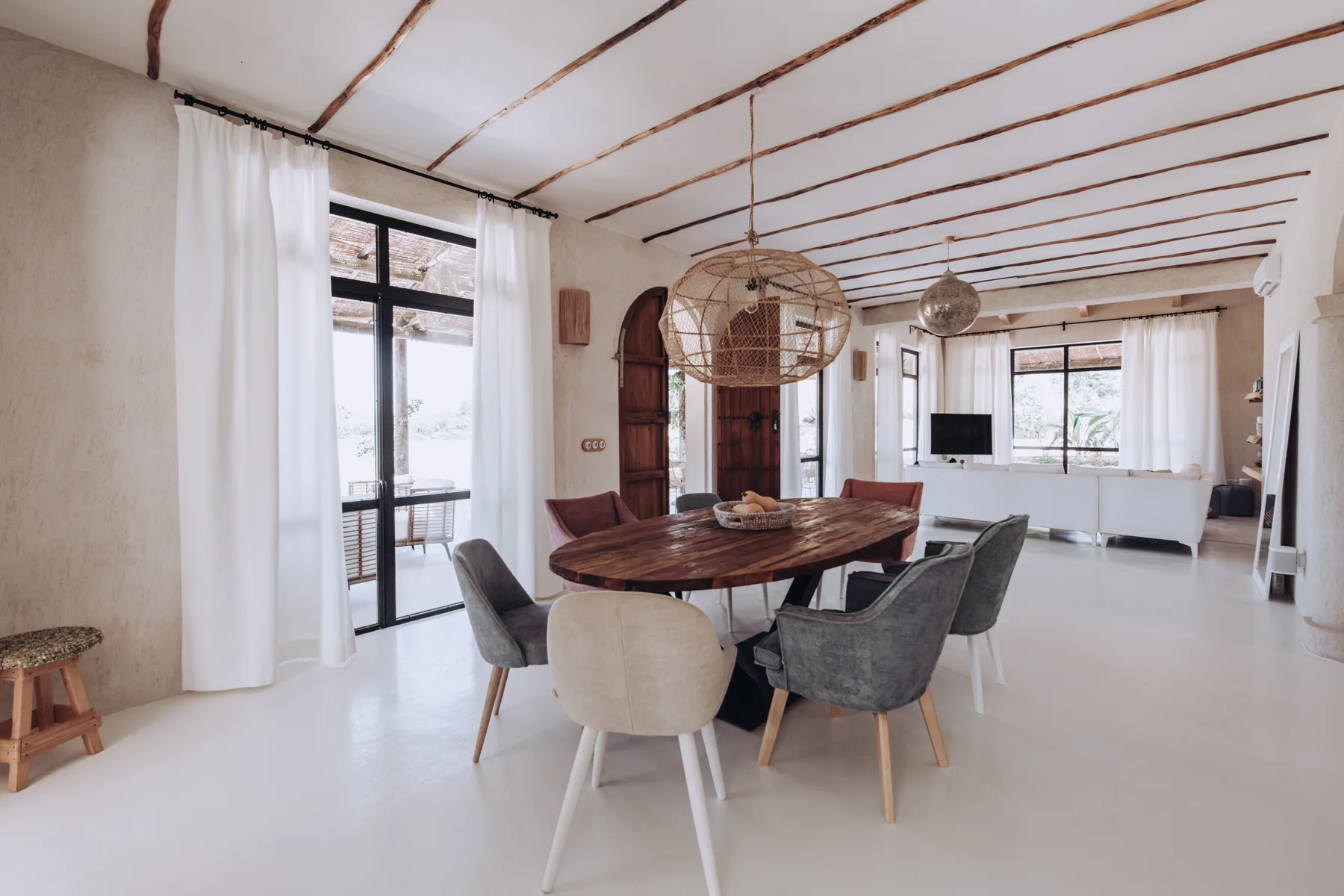 A dining area with a large wooden table and seating beneath exposed ceiling beams.