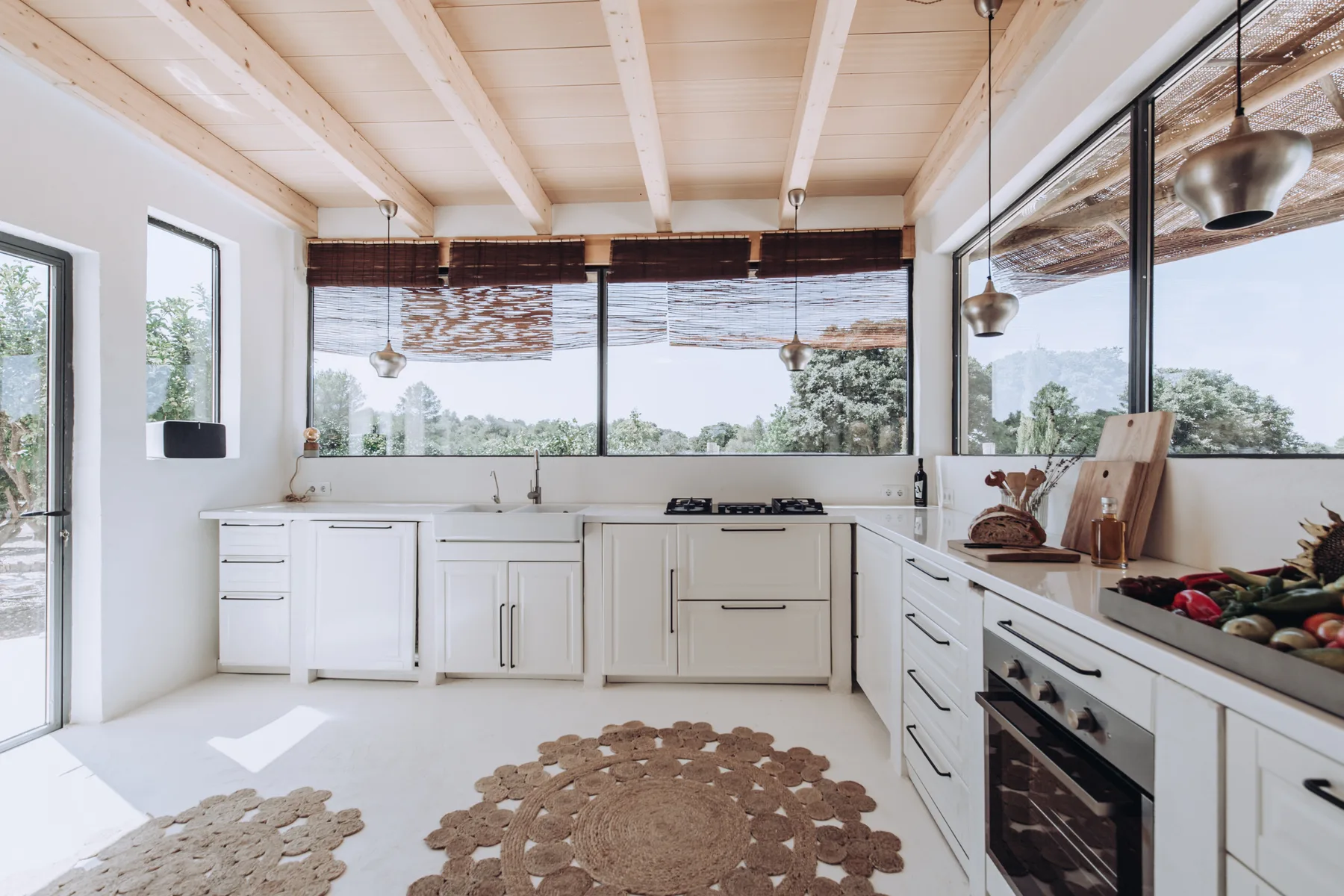 A bright kitchen with white cabinets, a cooking range, and wide windows.