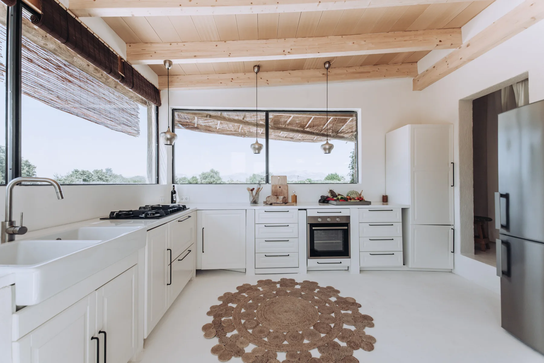 A bright kitchen with white cabinetry, a central range, and large windows.
