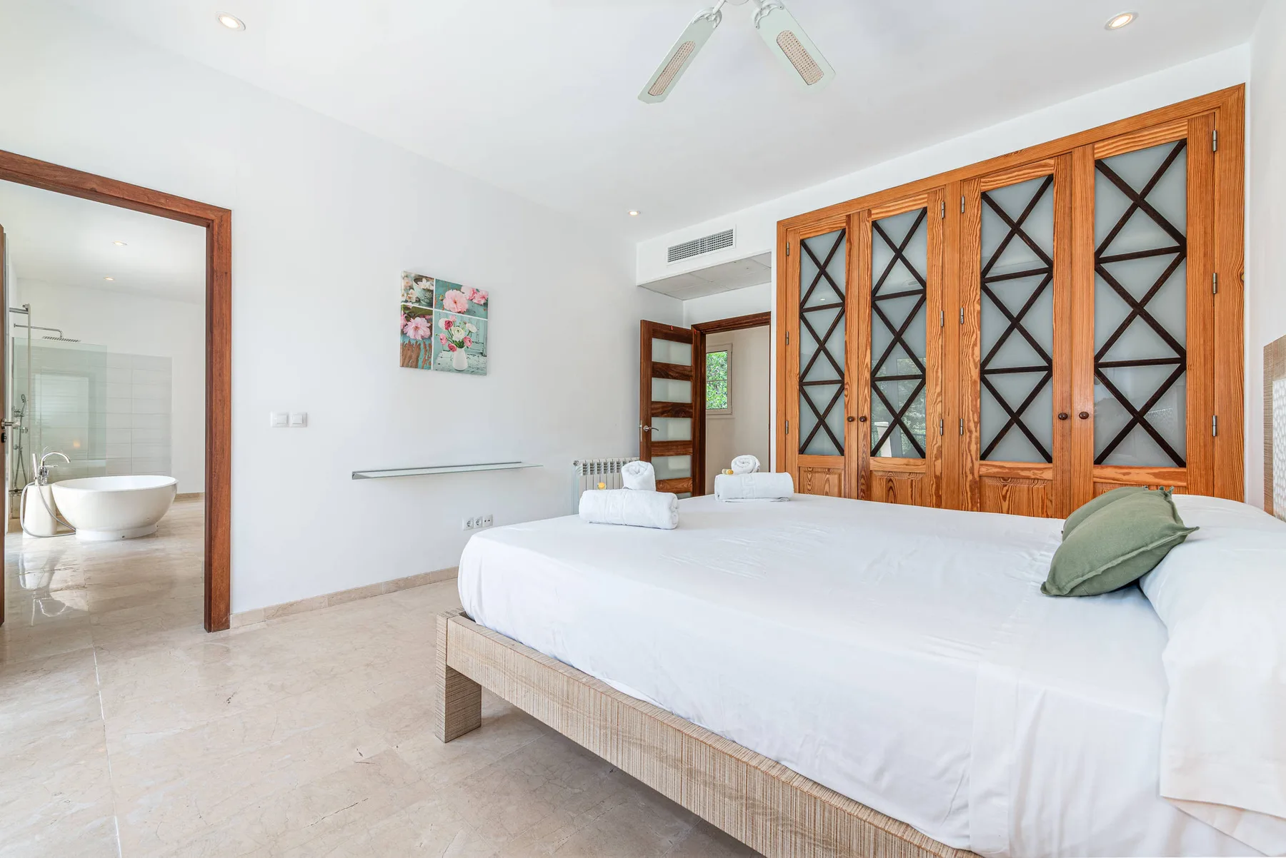 A bright bedroom with a large bed and wooden lattice doors.