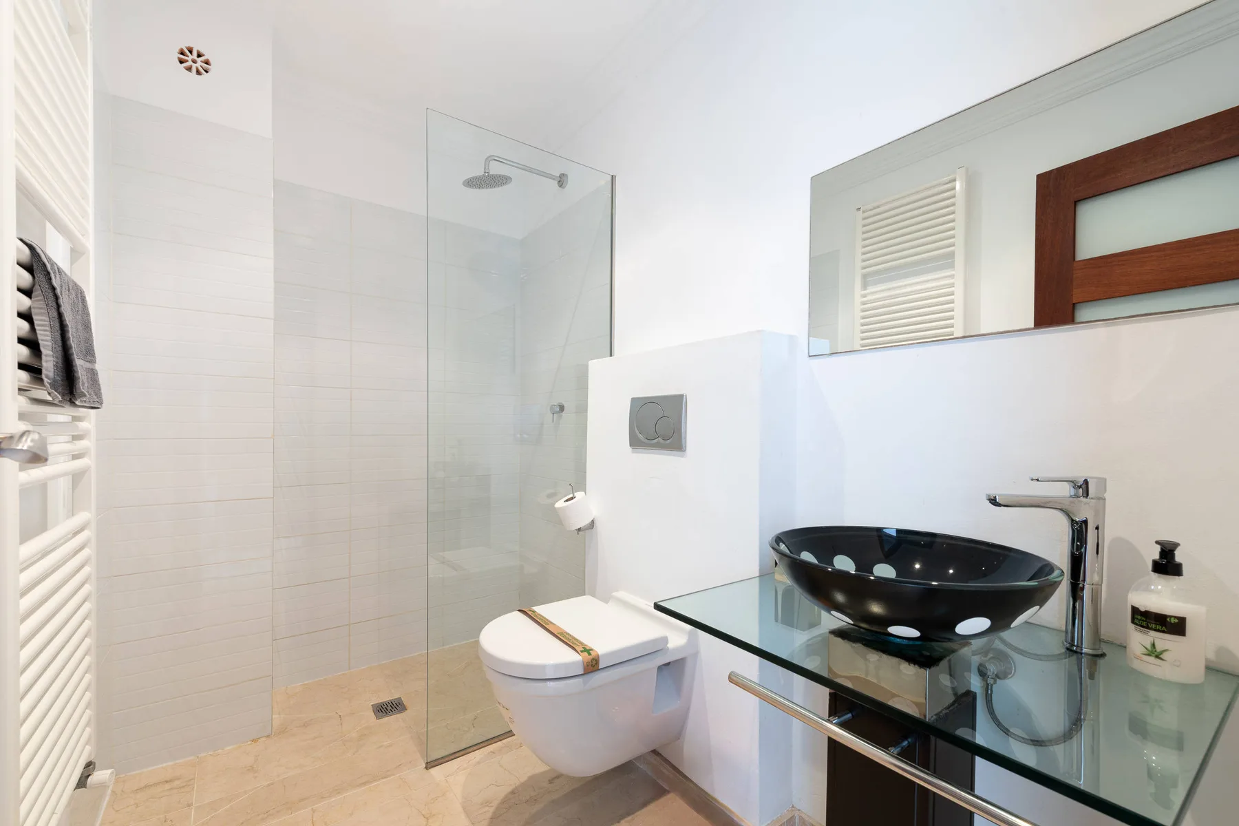A bright bathroom with a glass shower, toilet, and sink.