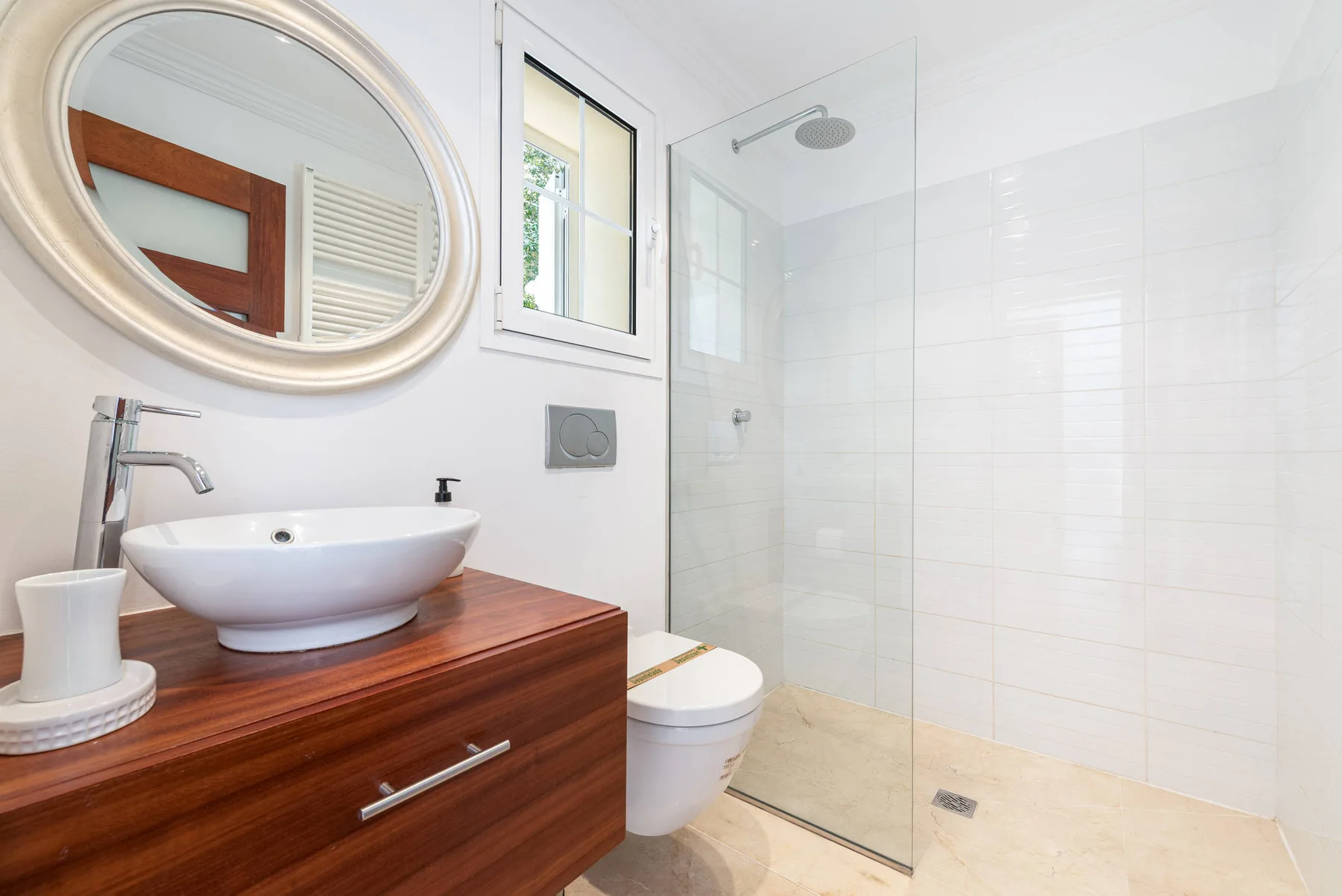 A bright bathroom with a sink vanity and glass-enclosed shower.