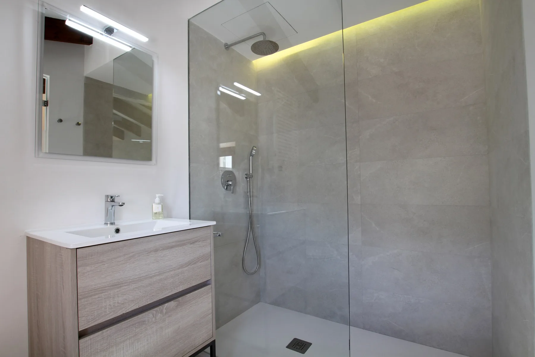 A modern bathroom with a vanity beside a glass-enclosed shower.