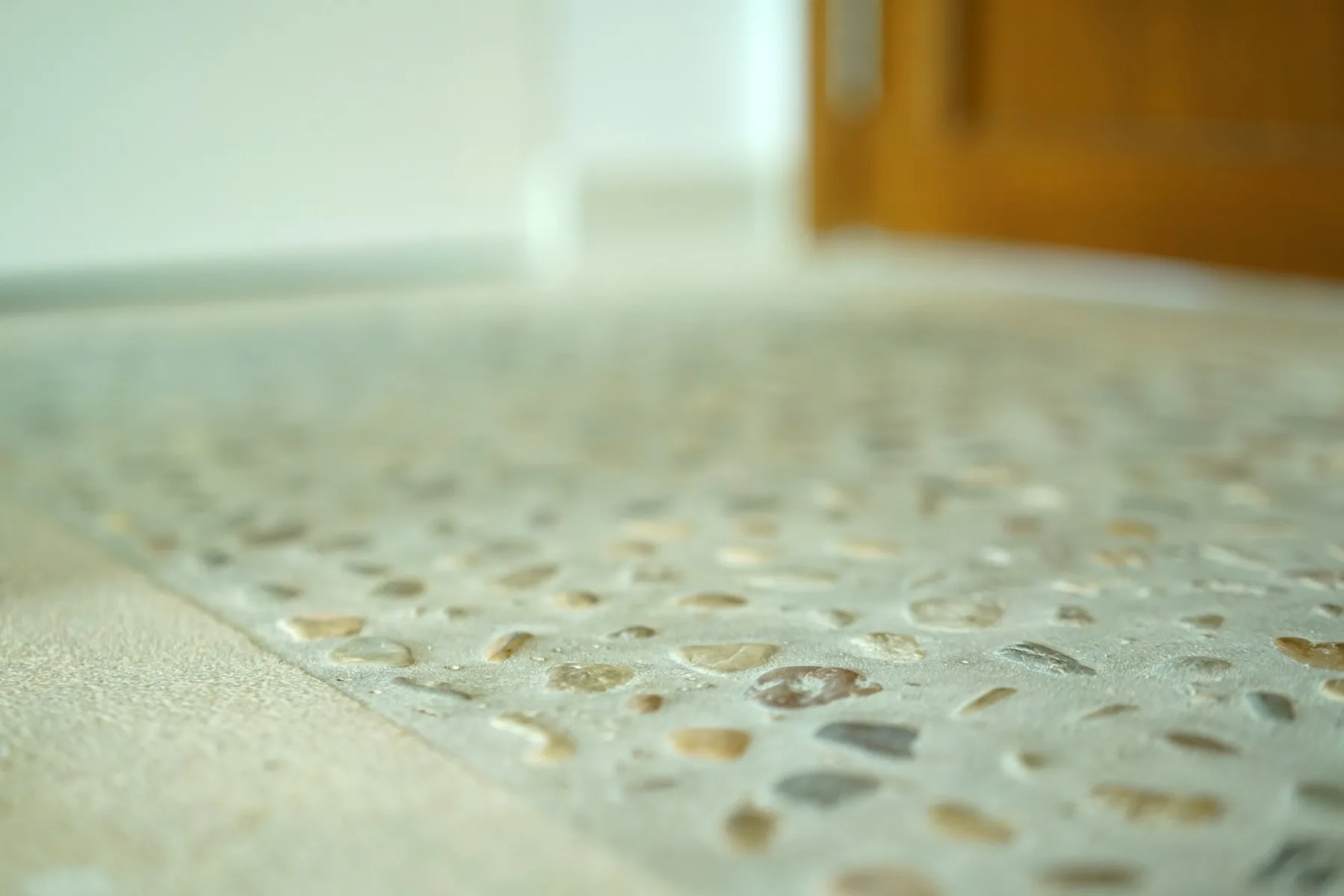 A close-up of a textured floor beside a wooden door.