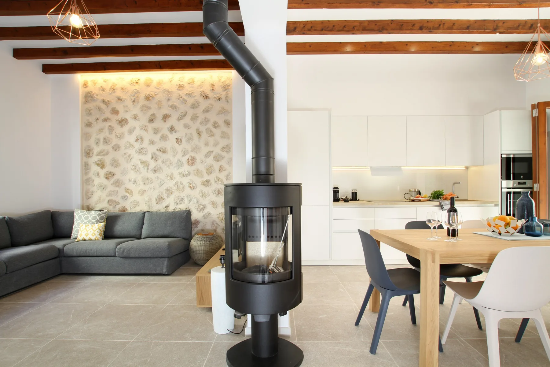 An open-plan living and dining area with a kitchen and a freestanding stove.