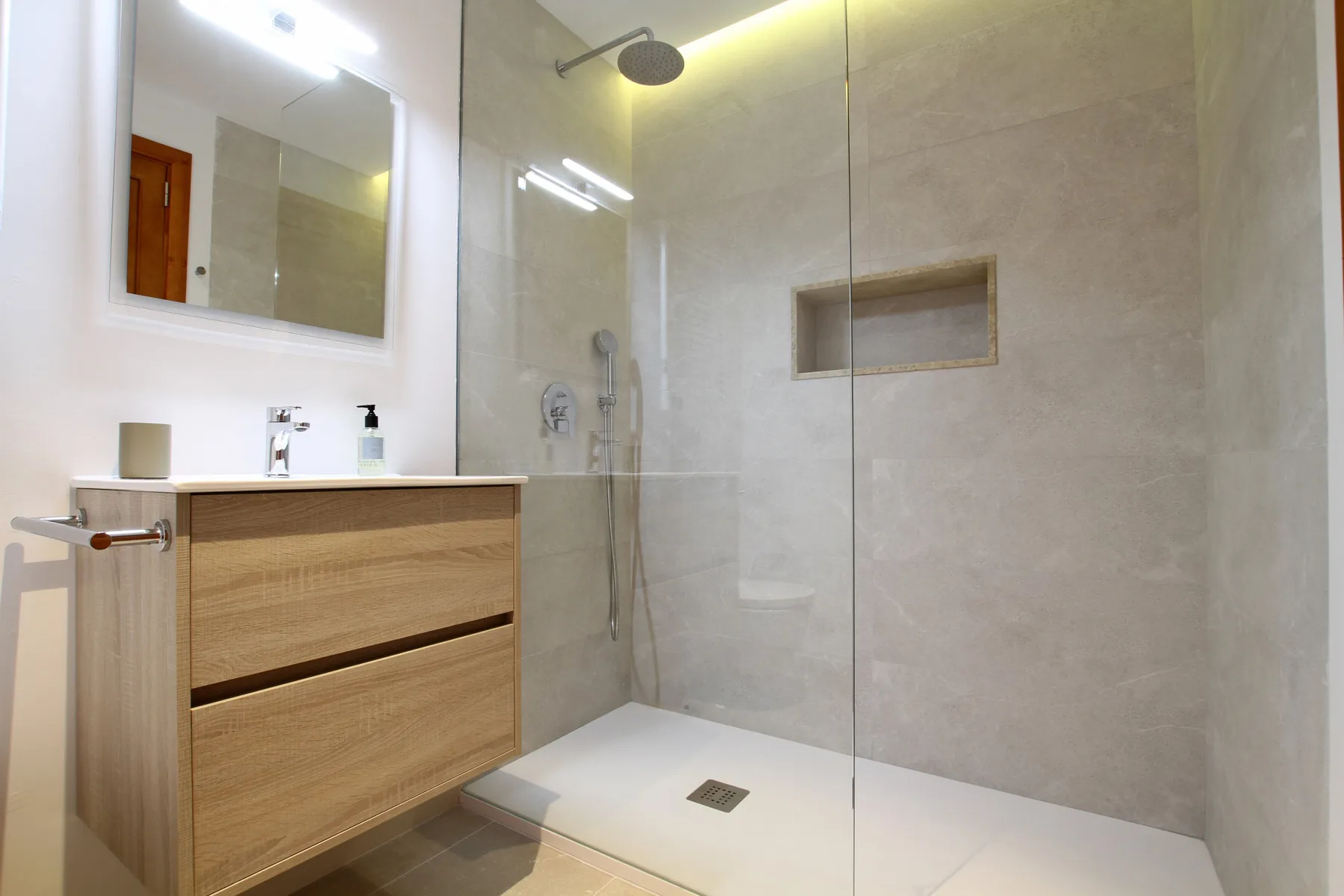 A modern bathroom with a wood vanity and a glass-enclosed shower.