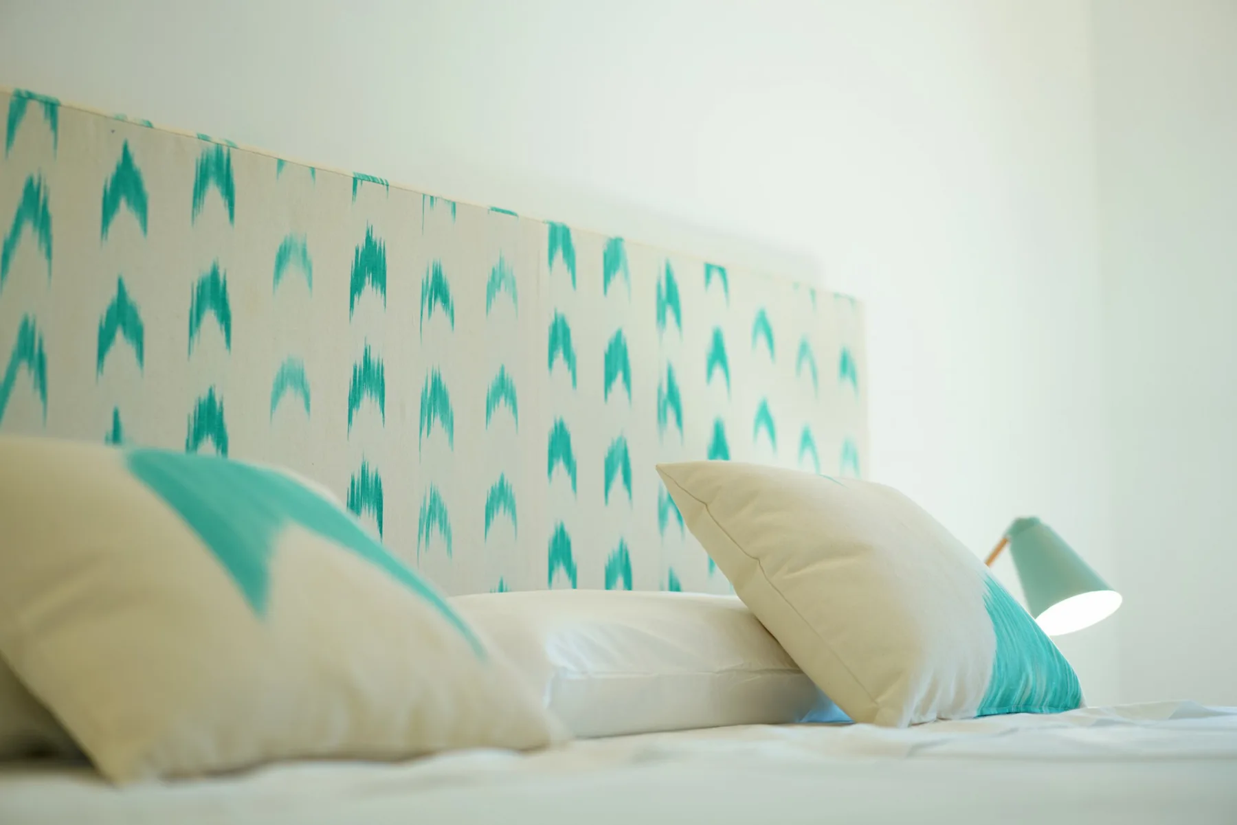 A bedroom scene with pillows against a patterned wall.