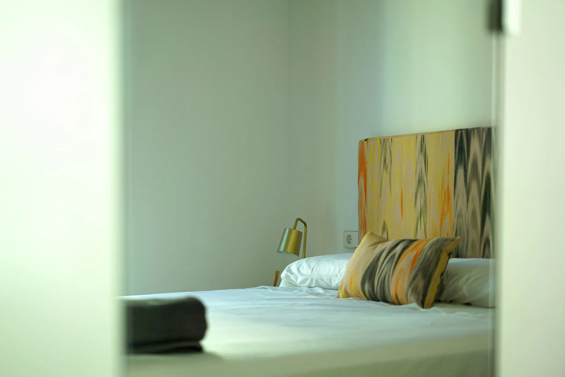 Bedroom with a bed and patterned cushions.
