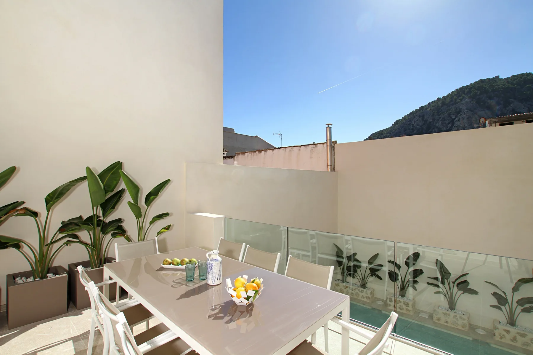 An outdoor dining area with a table and chairs beside a glass railing.