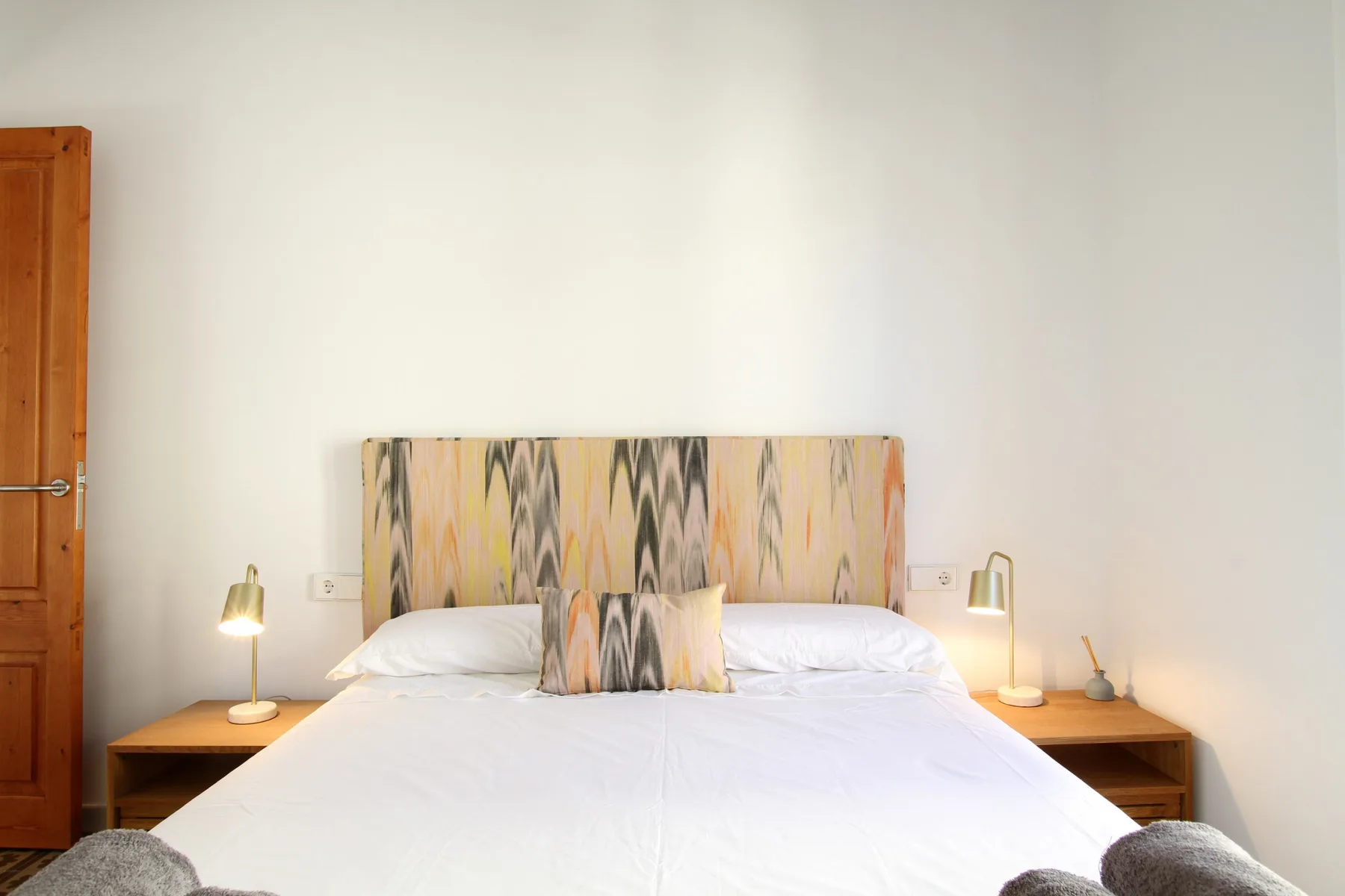 Bedroom with a bed dressed in white linens and a patterned headboard.