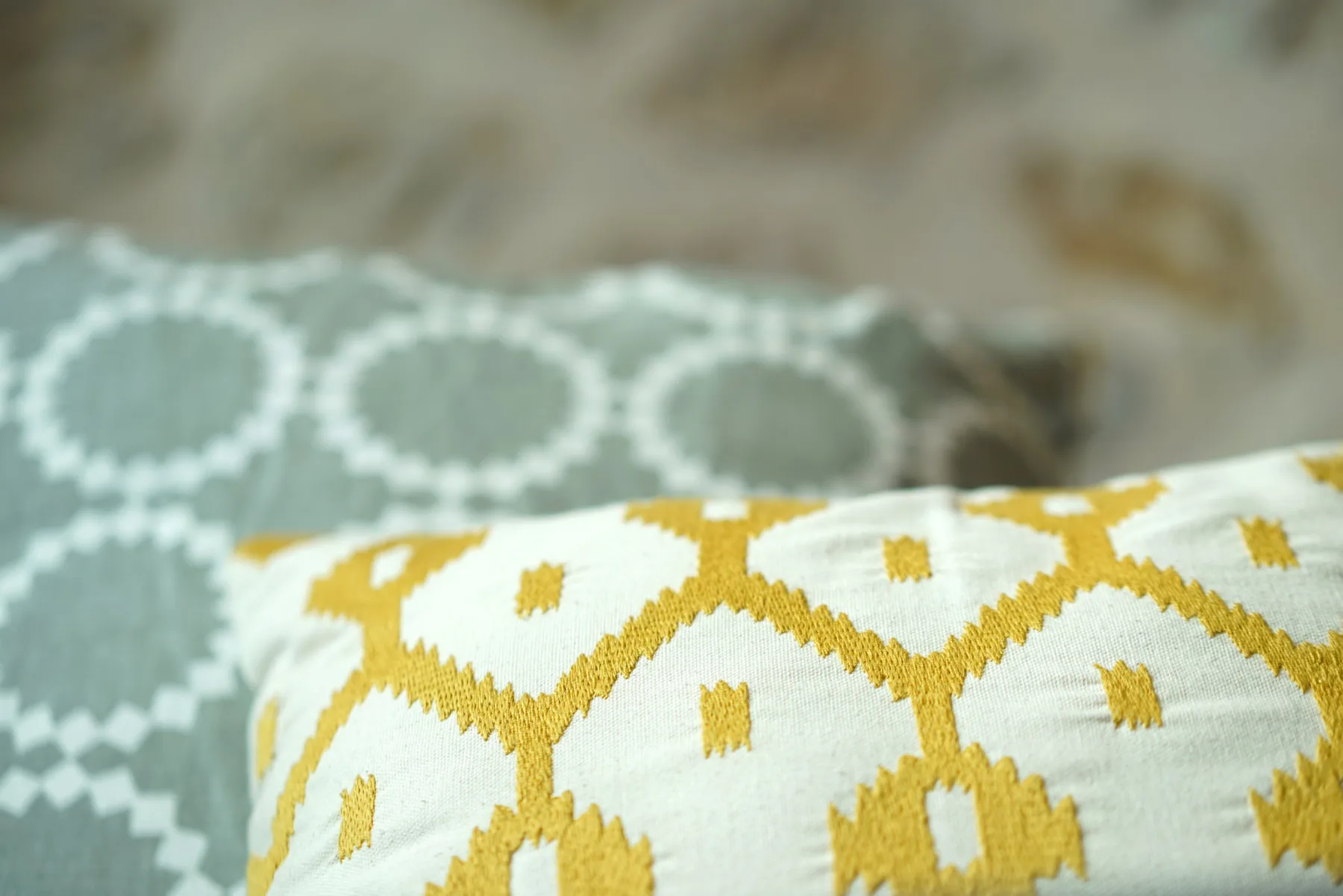 A close-up of patterned cushions with a soft gray textile in the background.