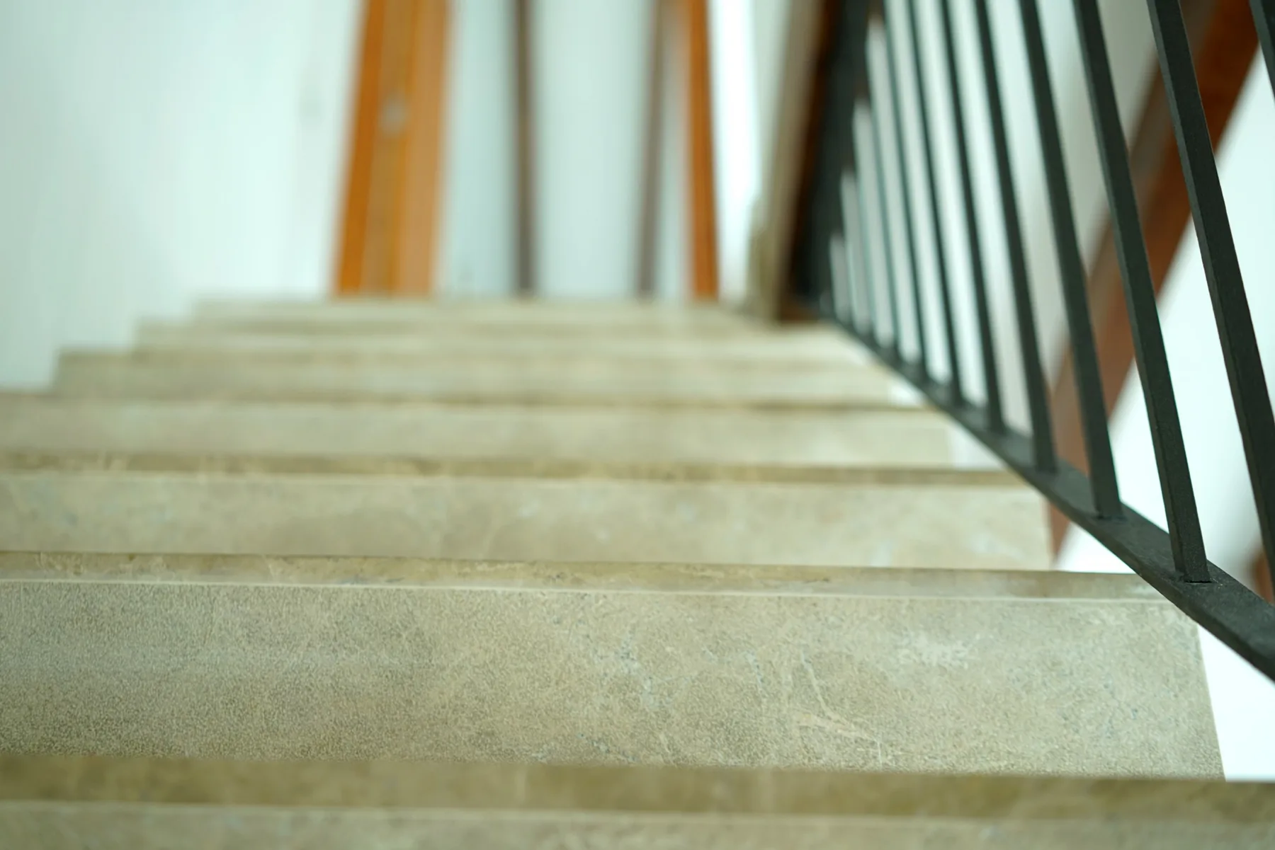 An indoor staircase with pale steps and a dark railing.