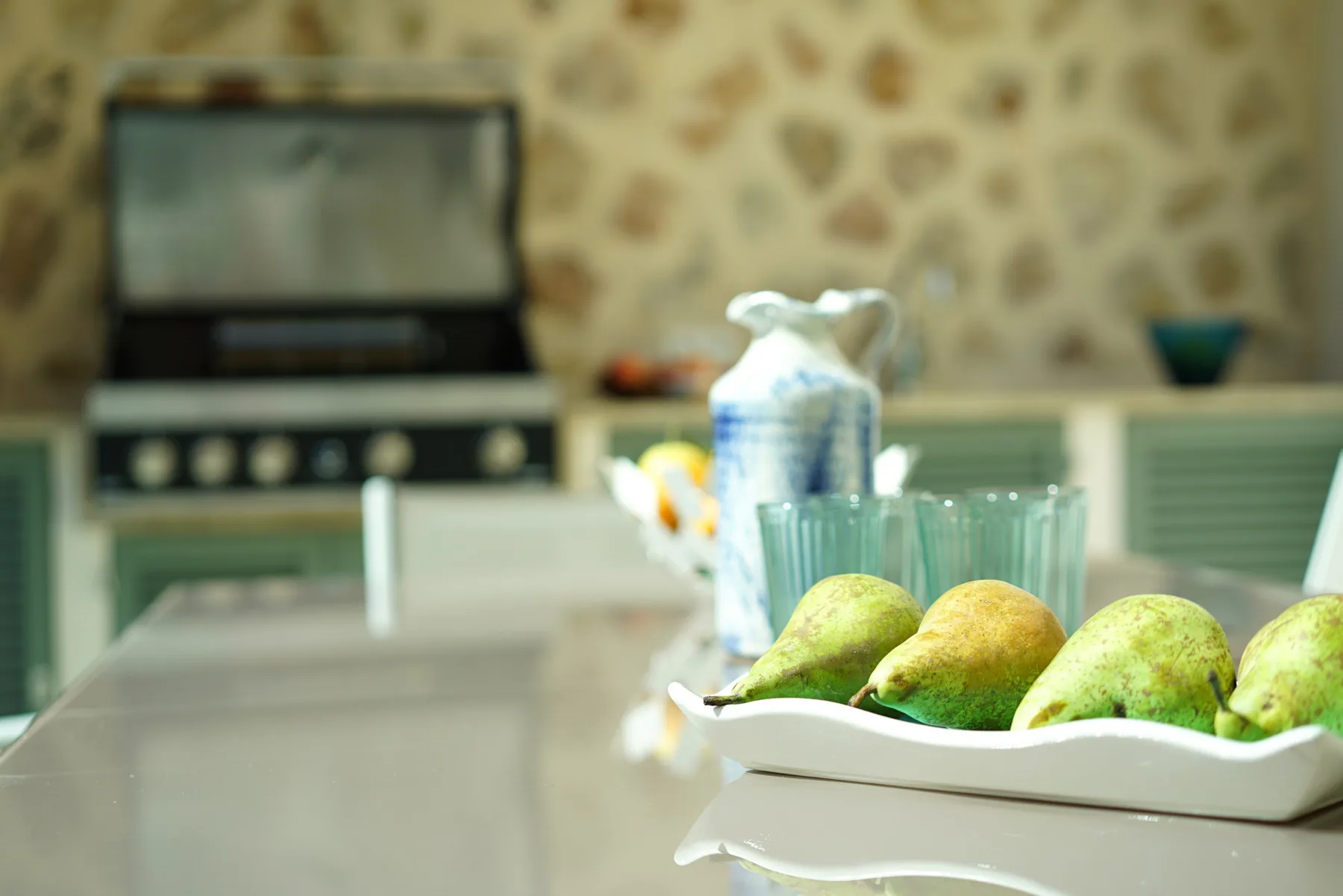 A kitchen counter displays a tray of fruit beside a pitcher.