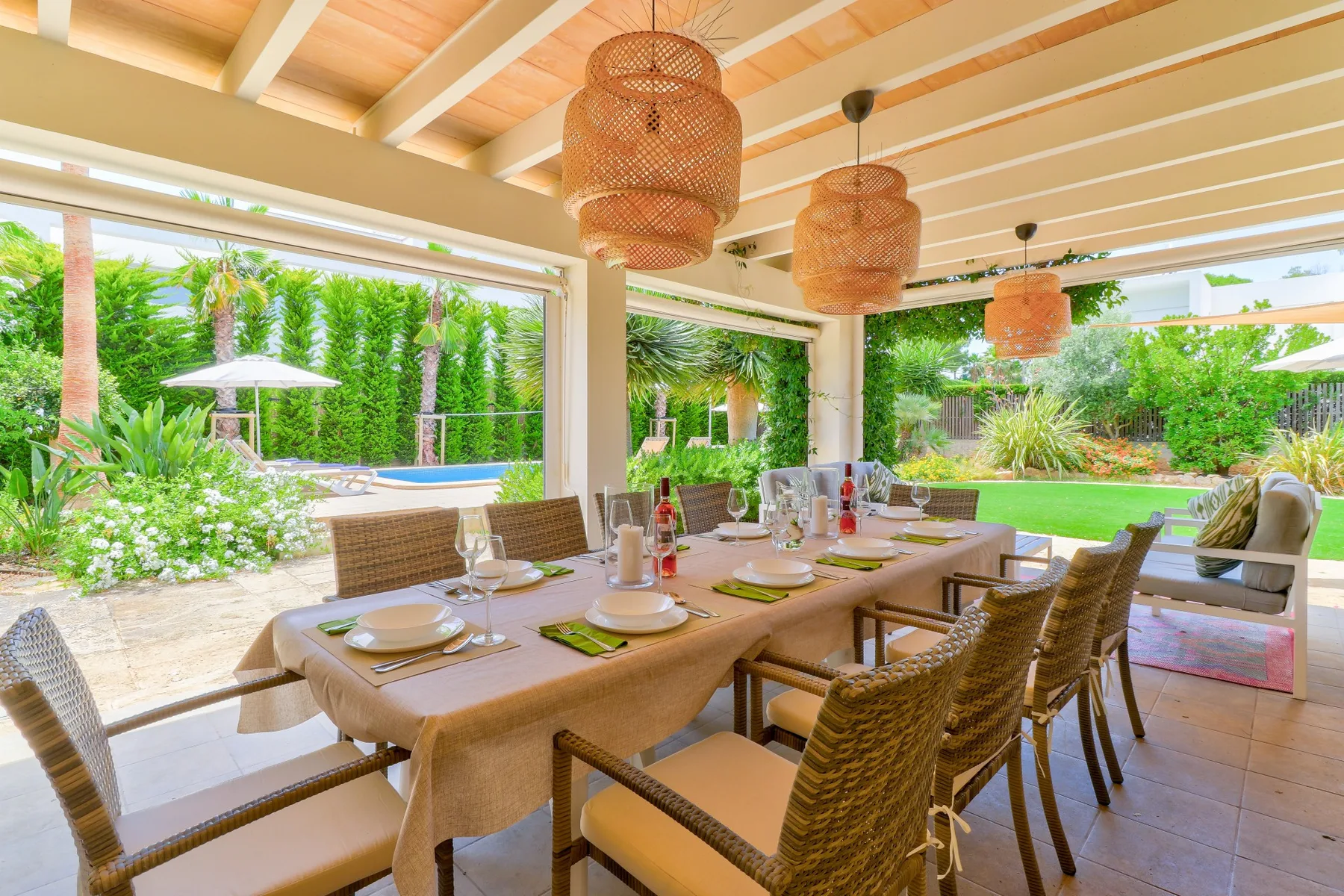 A covered outdoor dining area opens onto a garden and swimming pool.