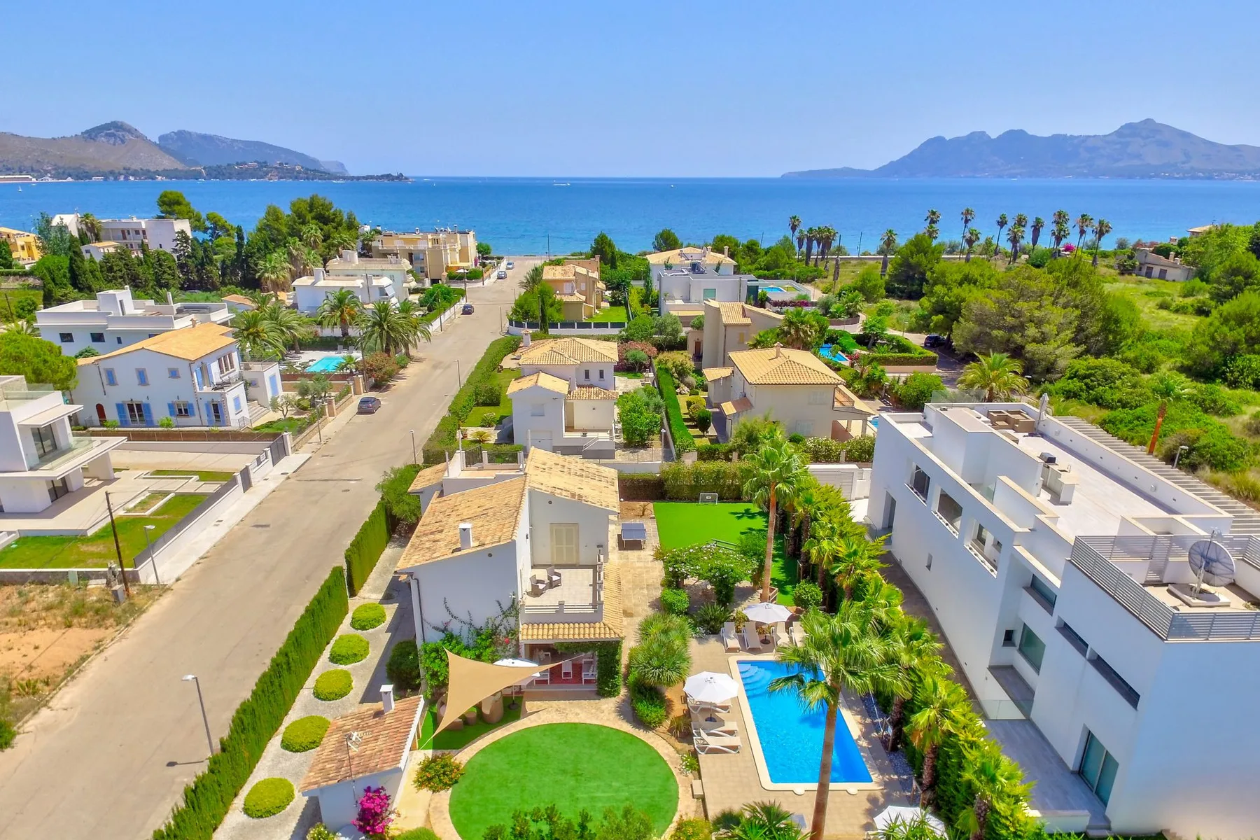 Aerial view of coastal homes with a swimming pool and the sea beyond.