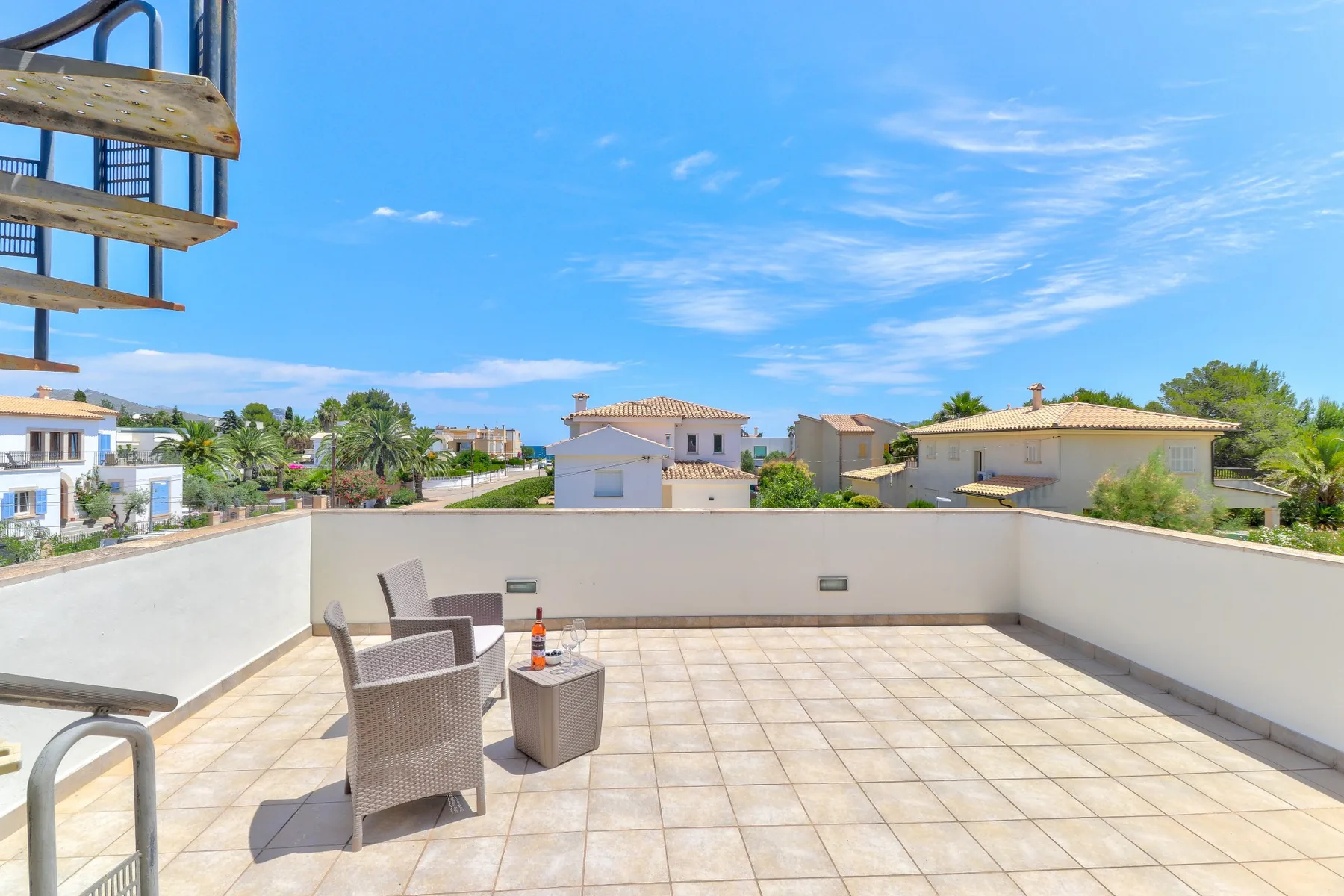 A sunny rooftop terrace with outdoor seating and views of nearby houses.