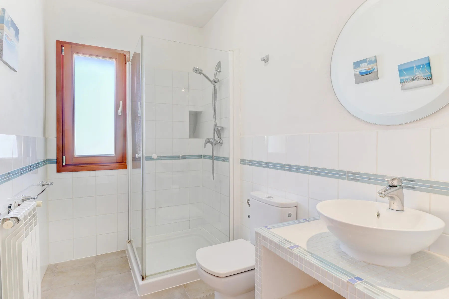 A bright bathroom with a glass shower, toilet, and sink.